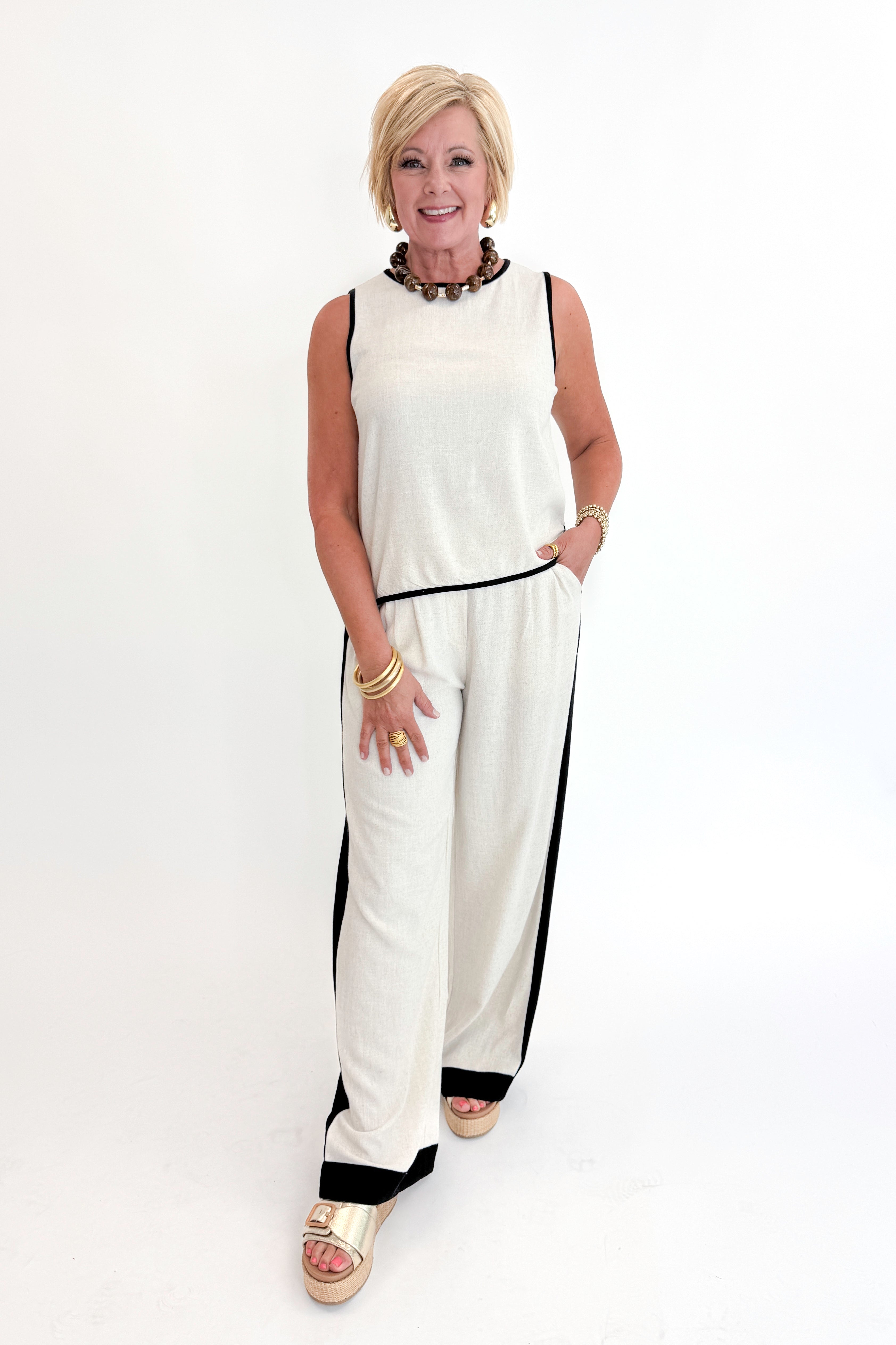 Front view of woman wearing Swagger Boutique’s Linen & Black Lined Tank with matching Linen & Black Stripe Pants against white studio background.