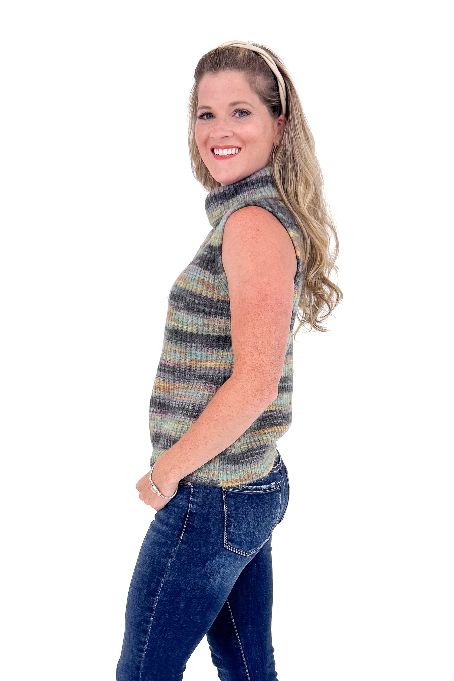 Woman wearing a sleeveless striped top and jeans on a white background