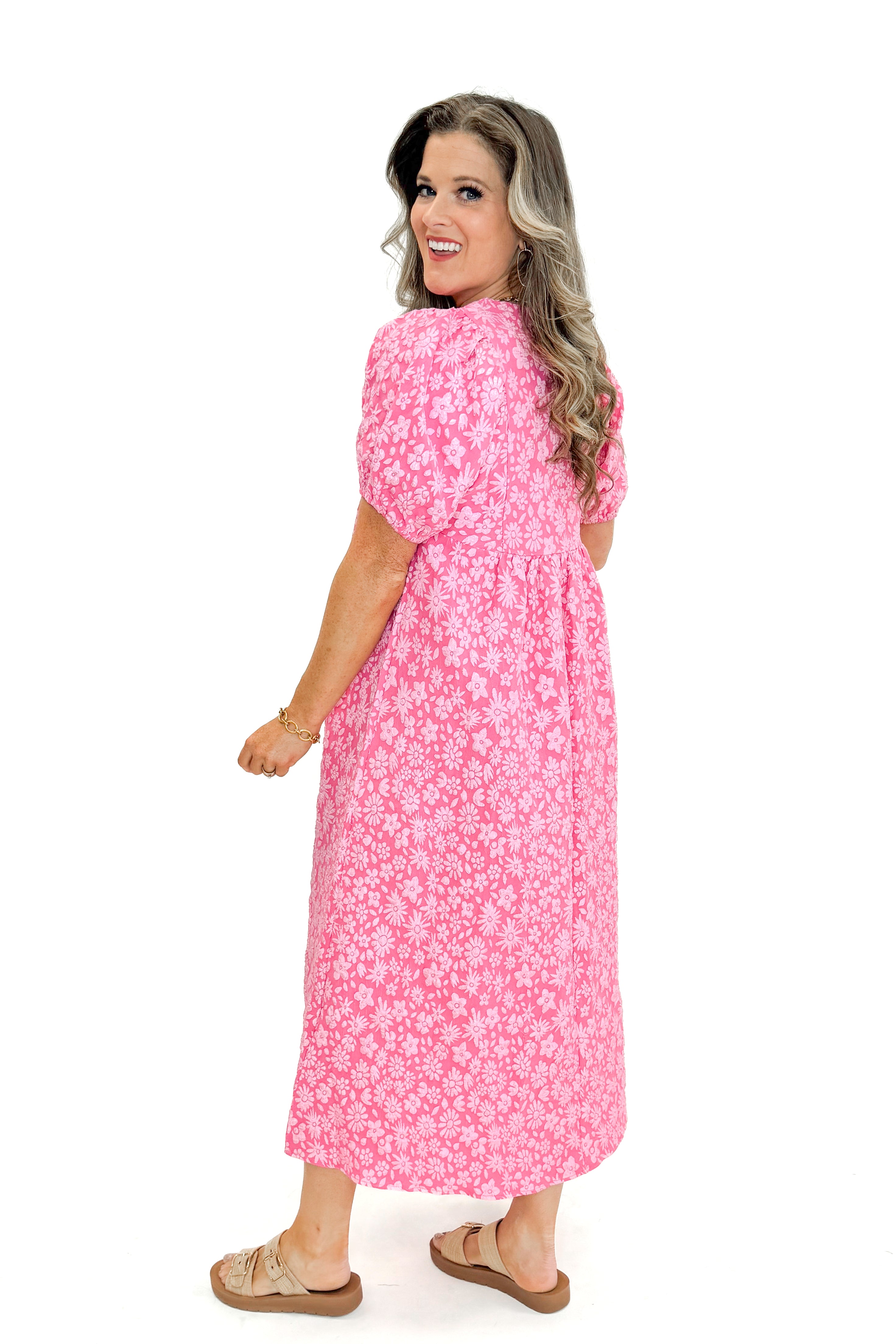 Side view of woman wearing Pink Floral Textured Puff Sleeve Midi Dress against white studio background.