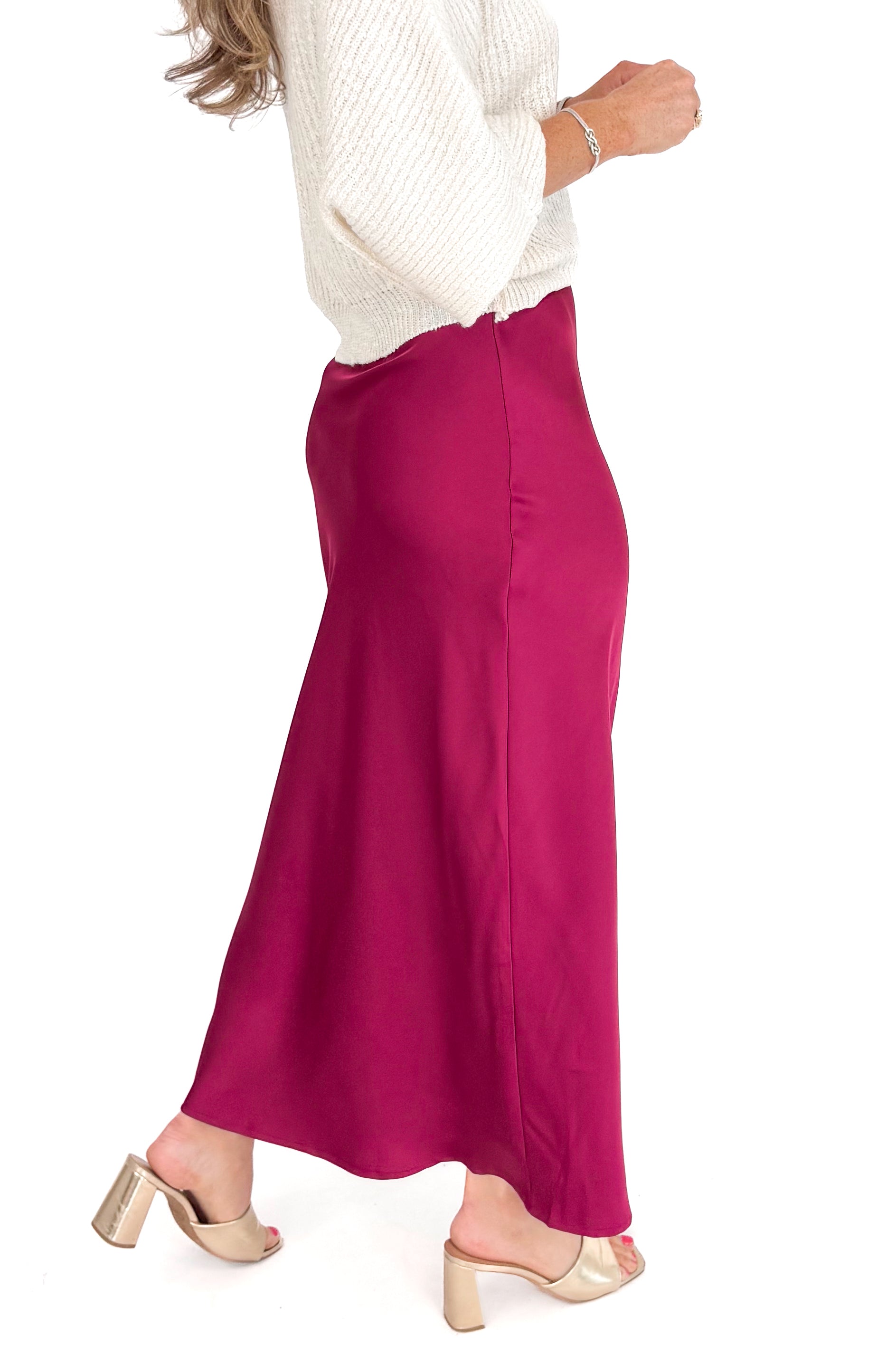 Person wearing a burgundy skirt and white sweater on a white background