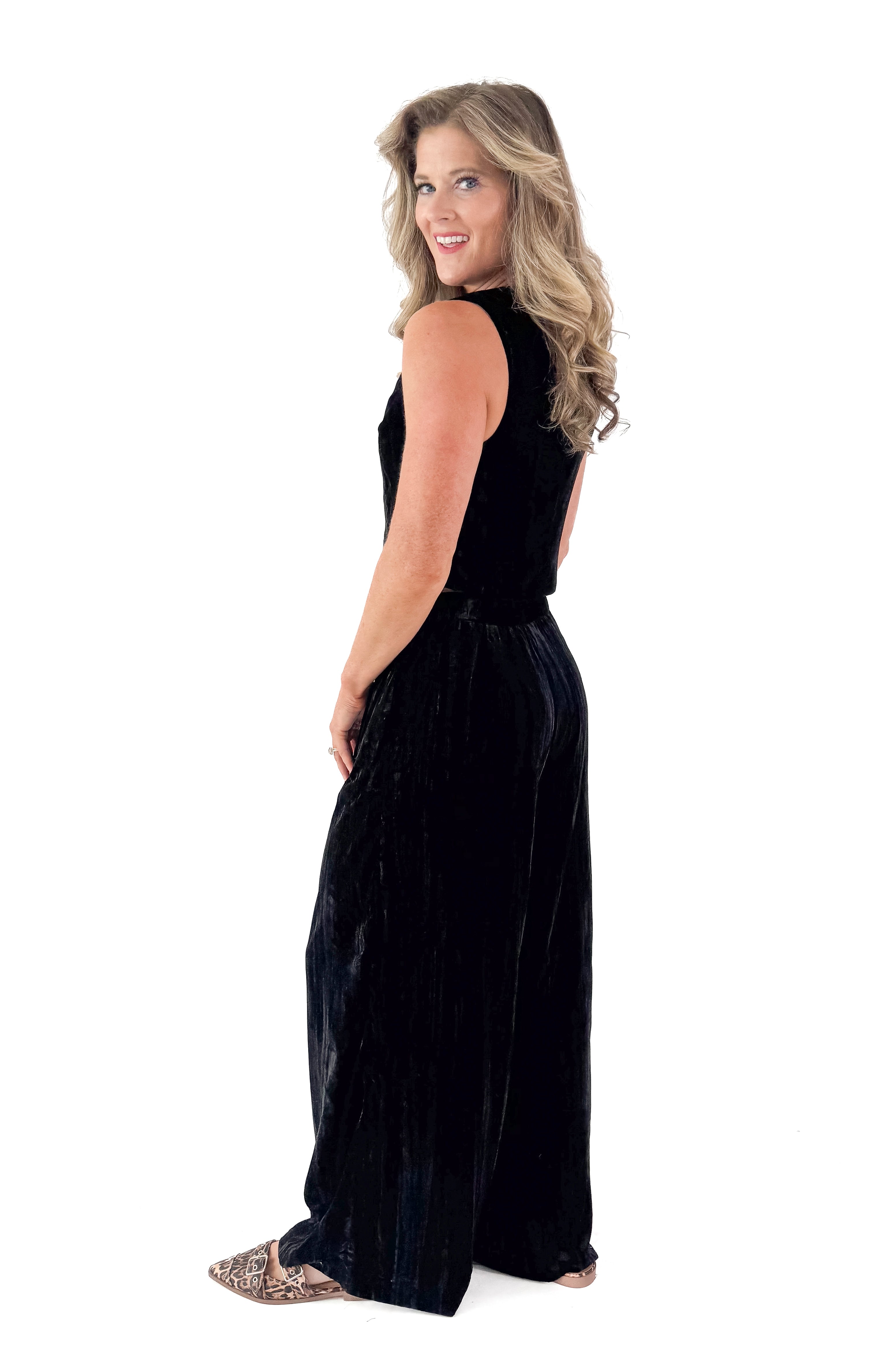Side view of woman wearing Black Textured Velvet Wide Leg Pants and matching tank against white studio background.