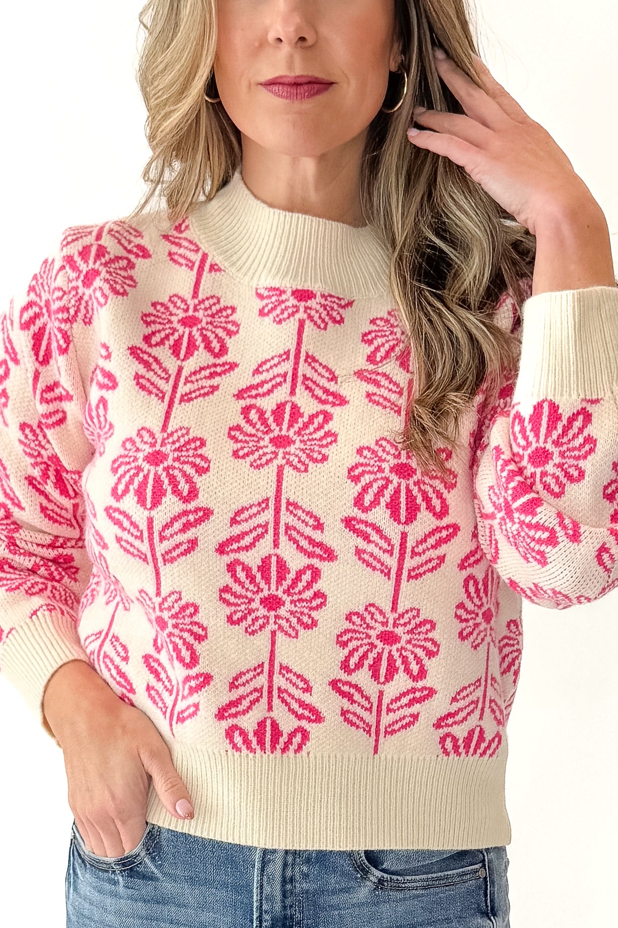 Front detailed view of woman wearing Cream and Pink Floral Patterned Sweater with jeans against white studio background.