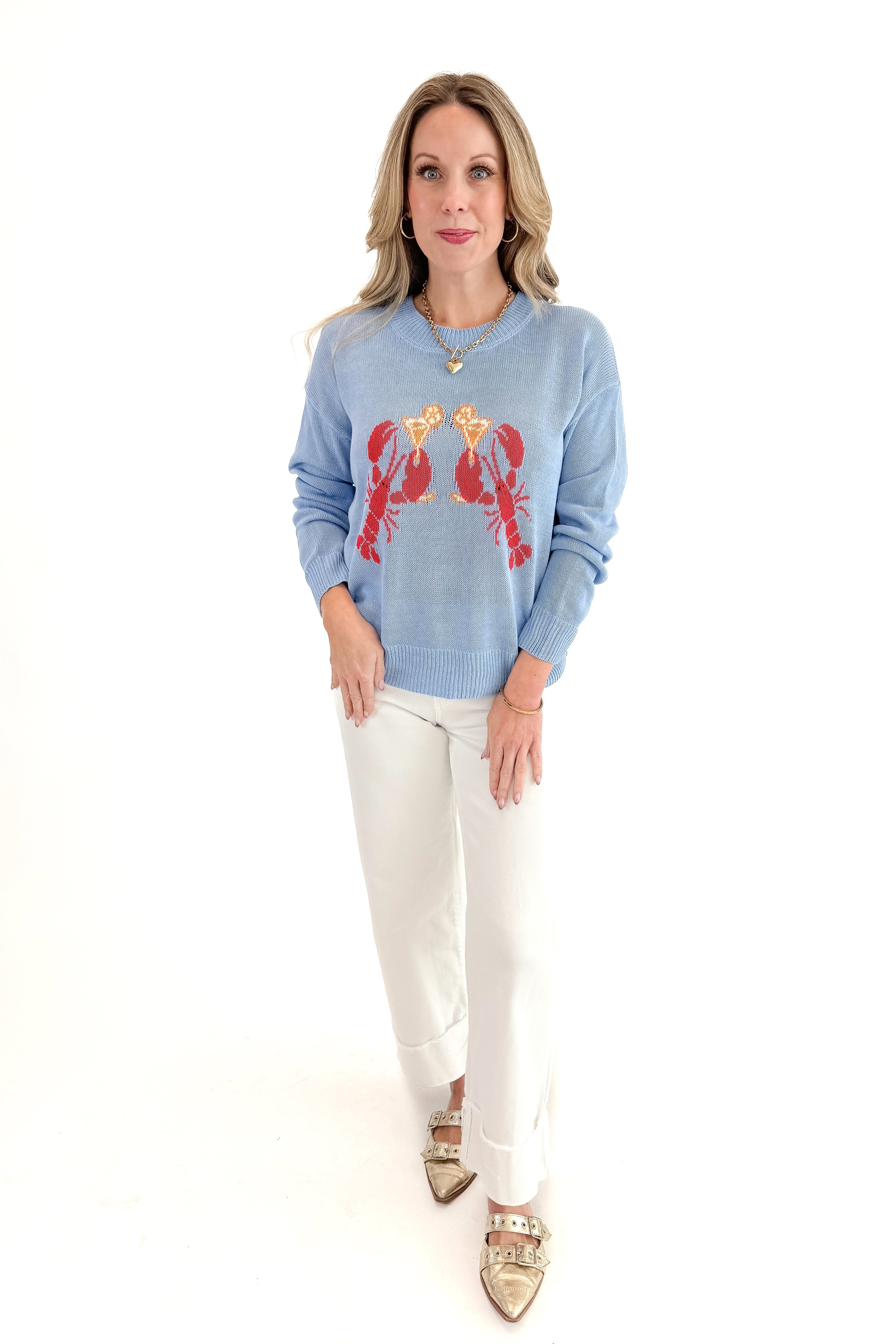 Front view of woman wearing Blue Lobster Graphic Sweater with jeans against white studio background.