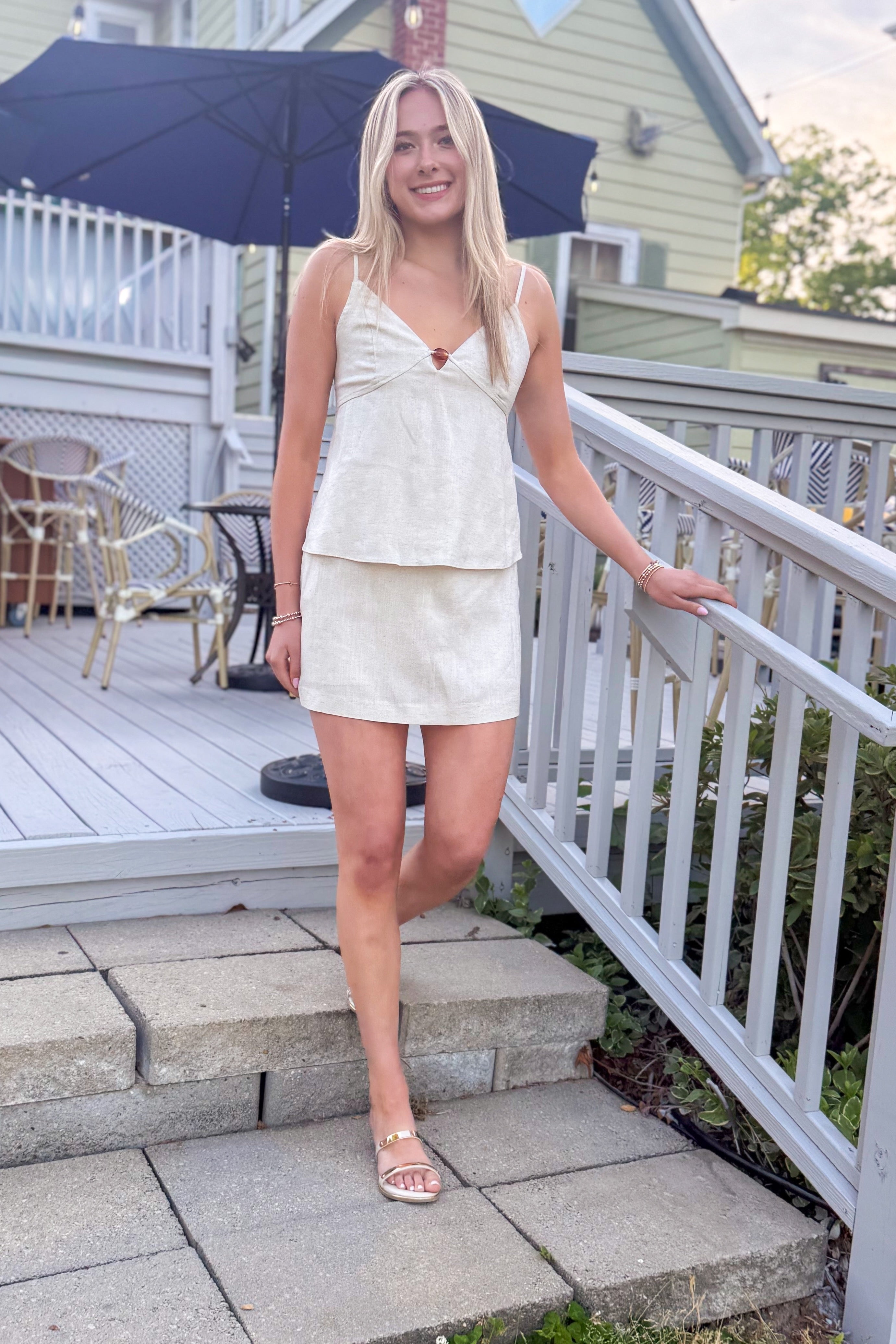 Front view of woman wearing Linen Bead Detail Top with matching Linen Mini Skirt walking outside at a restaurant.