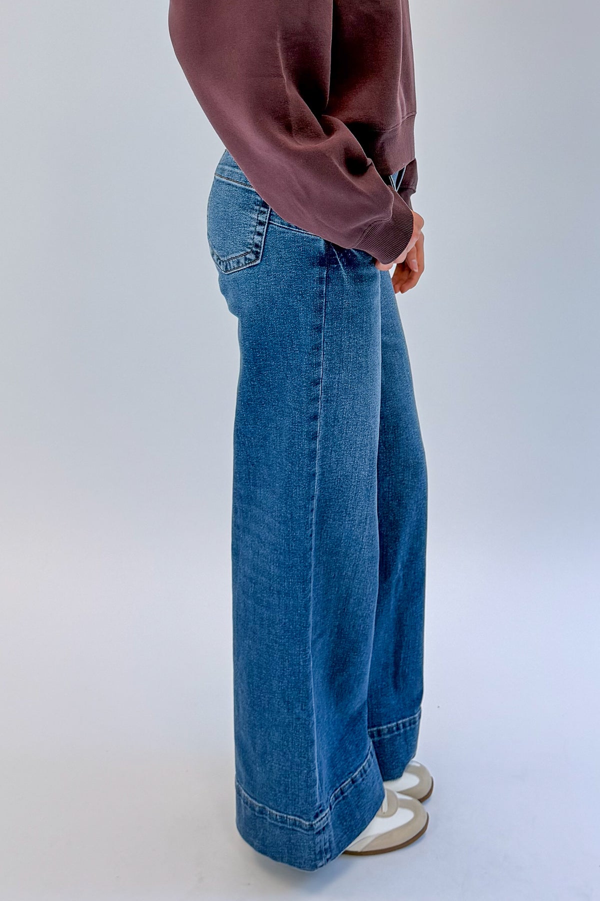 Side view of woman wearing Swagger Boutique’s Maya Wide Leg Jeans In Medium Wash- Journey by Kut from the Kloth against white studio background.
