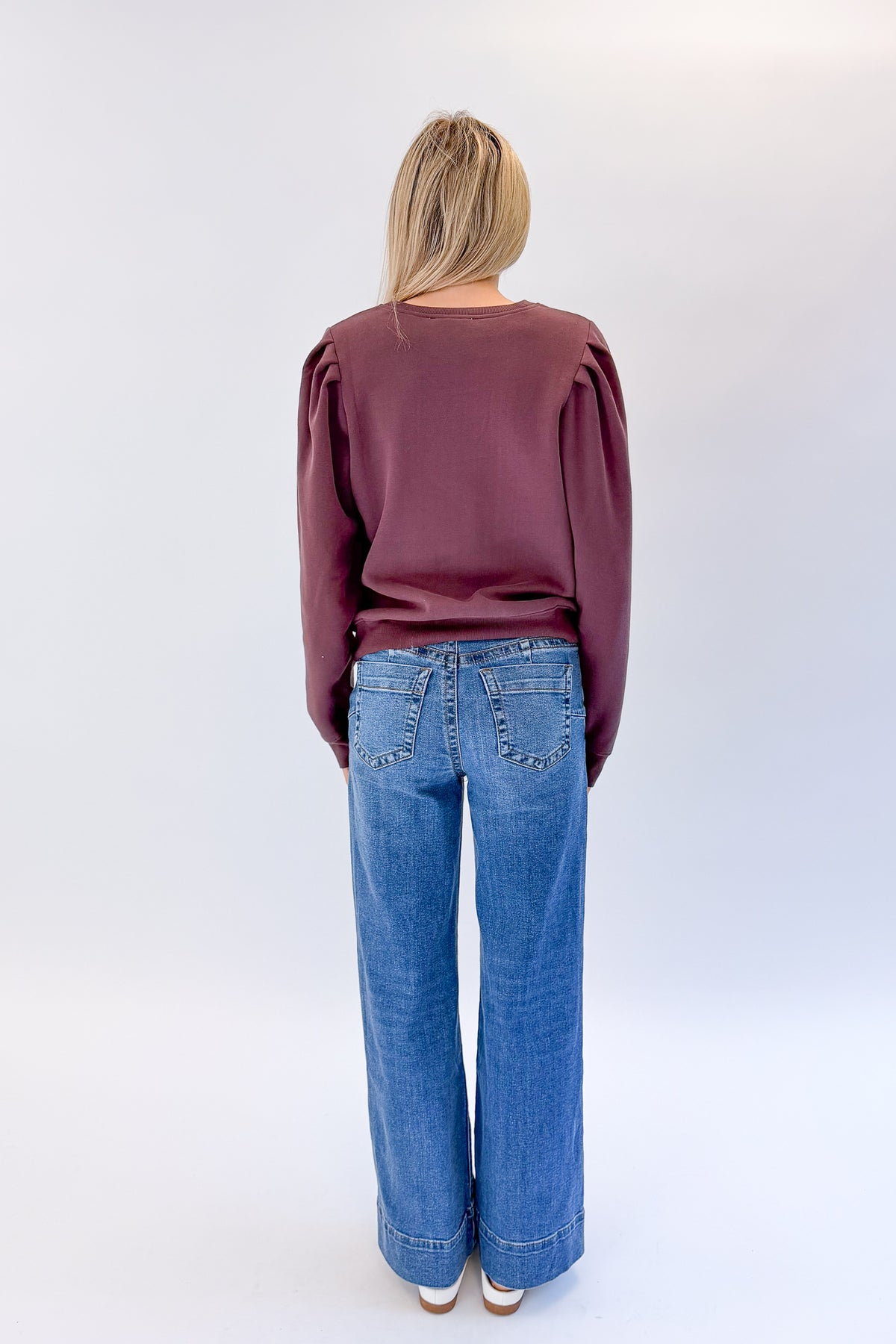 Back view of woman wearing Swagger Boutique’s Maya Wide Leg Jeans In Medium Wash- Journey by Kut from the Kloth against white studio background.
