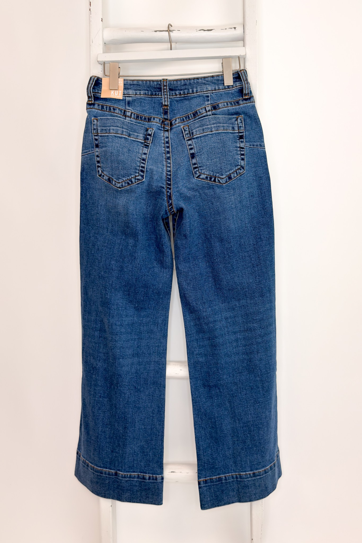 Swagger Boutique’s Maya Wide Leg Jeans In Medium Wash- Journey by Kut from the Kloth hanging against white studio background back view.