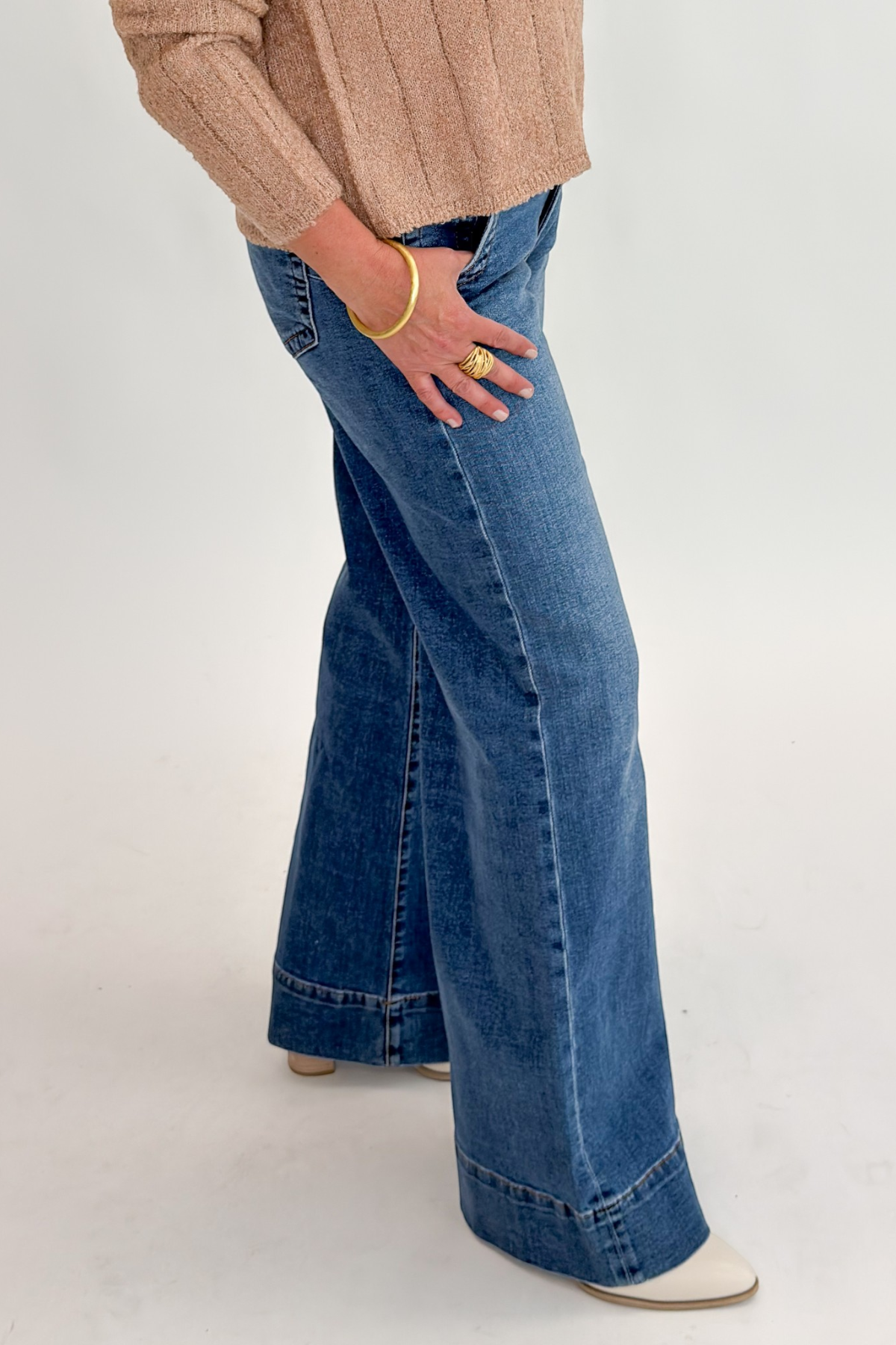 Side detail view of woman wearing Swagger Boutique’s Maya Wide Leg Jeans In Medium Wash- Journey by Kut from the Kloth against white studio background.