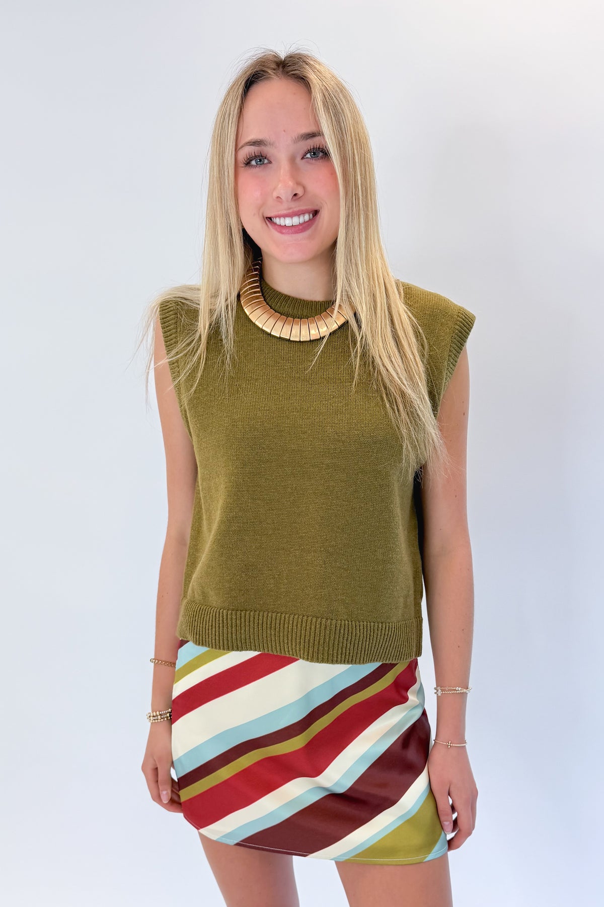 Front view of woman wearing Swagger Boutique’s sweater with Multi Striped Satin Mini Skirt against white studio background.