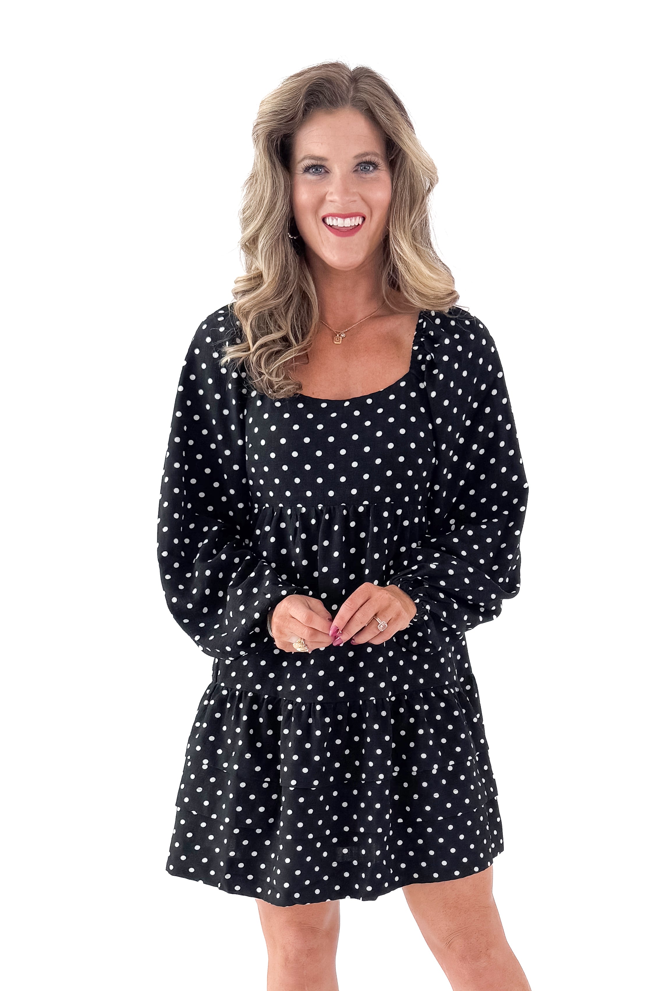Front view of woman wearing polka dot dress and boots against white studio background.