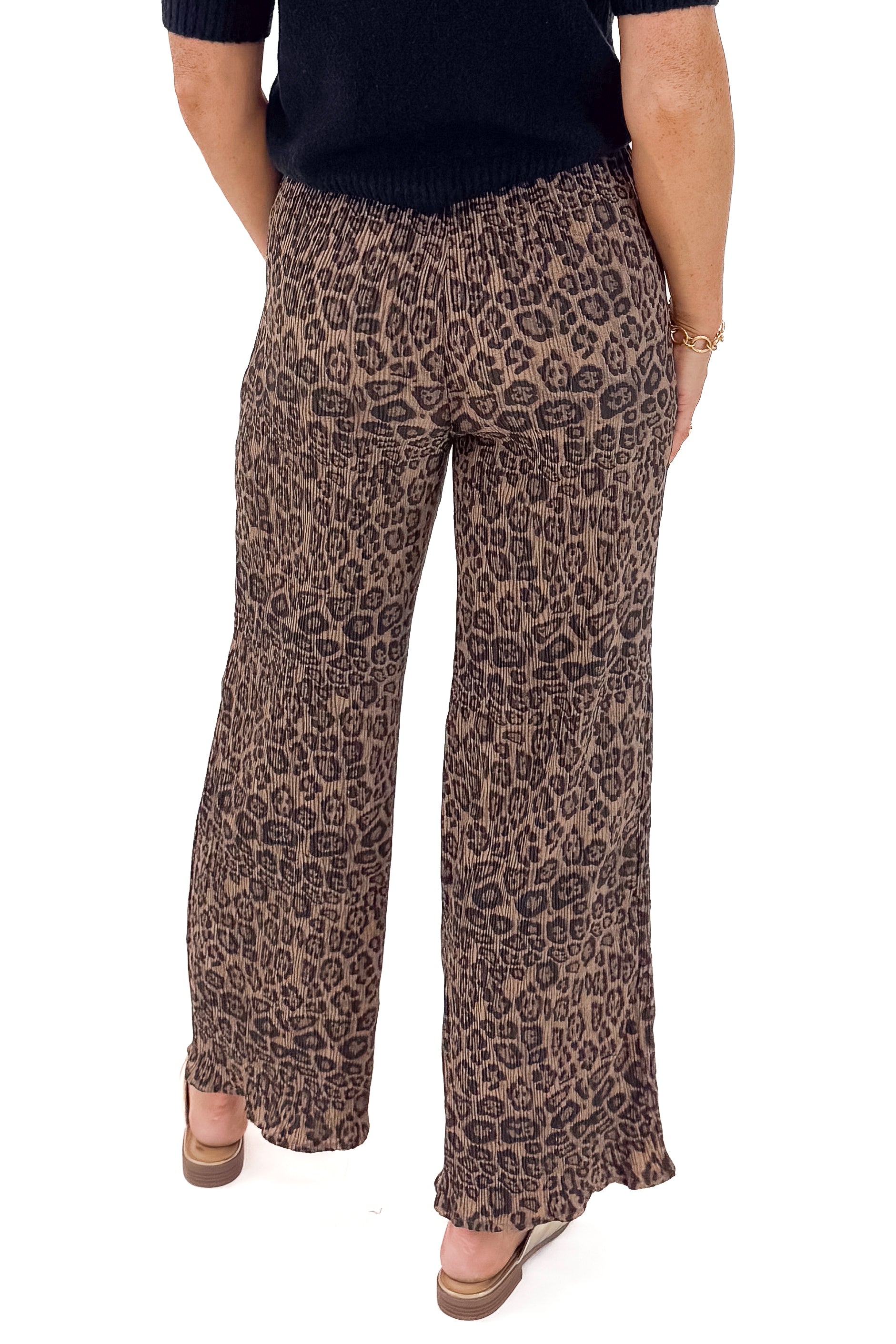 Back view of woman wearing Leopard Pleated Pants with sweater against white studio background.