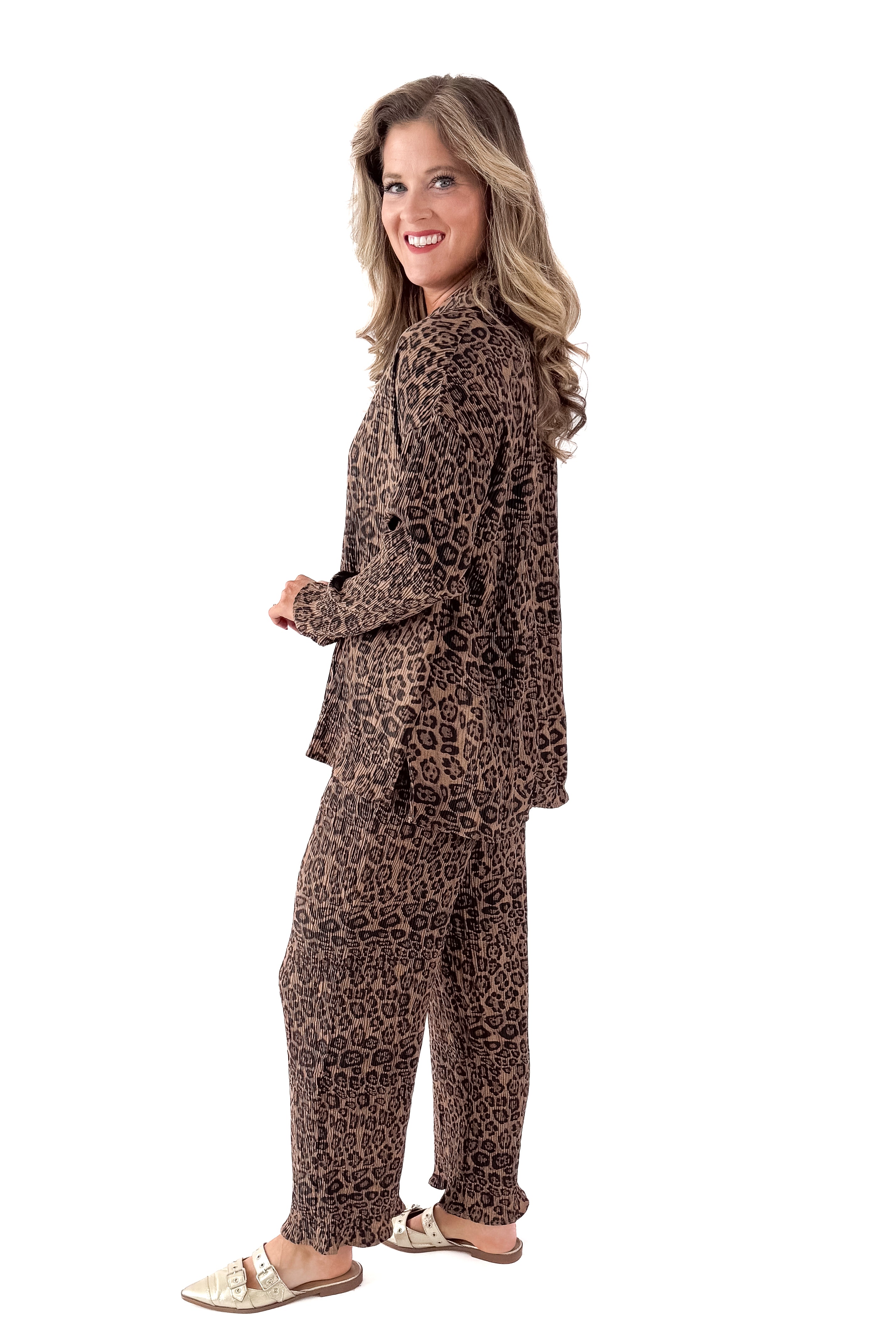 Side view of woman wearing Leopard Pleated Pants with matching top against white studio background.