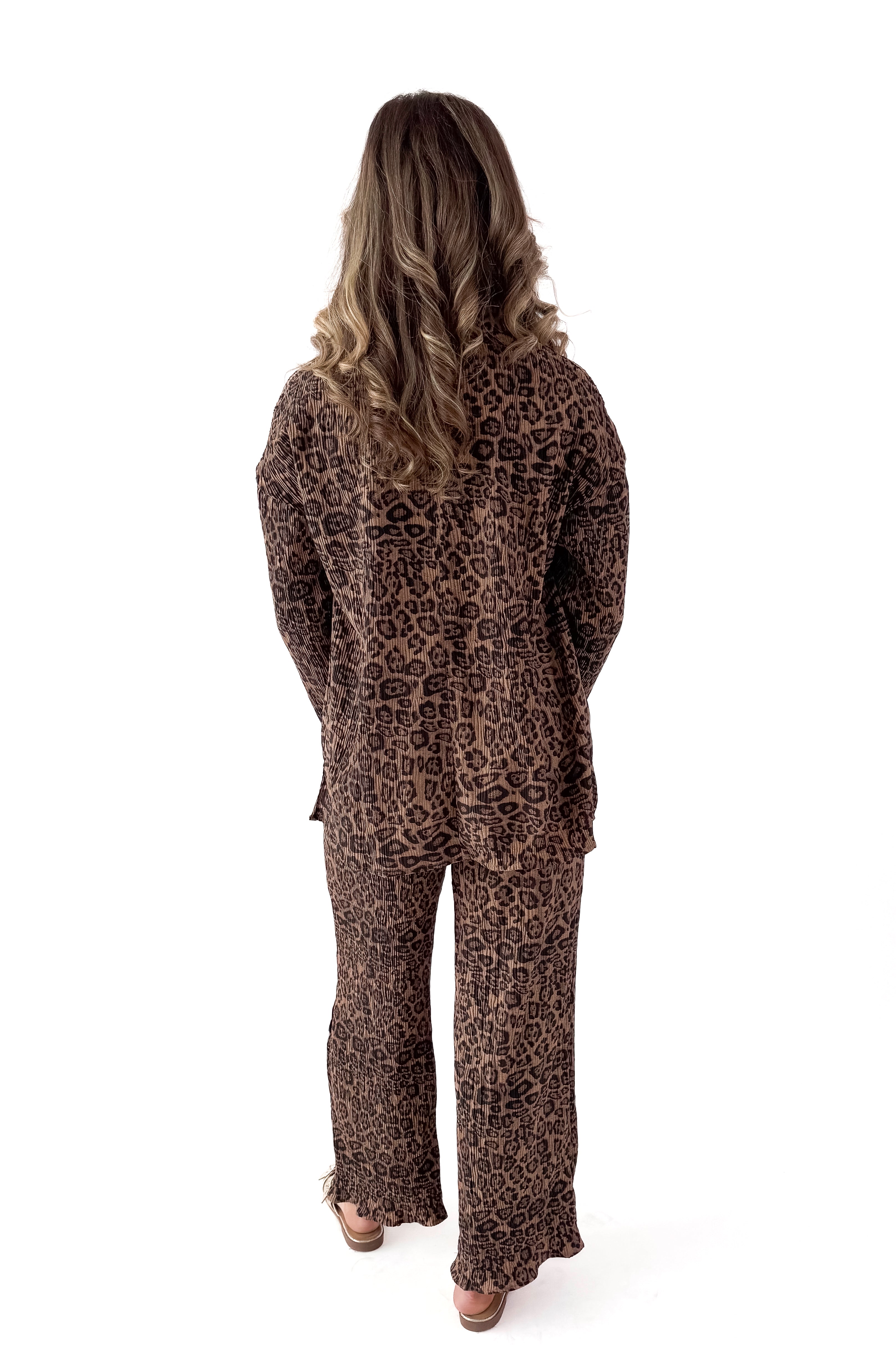 Back view of woman wearing Leopard Pleated Pants with matching top against white studio background.