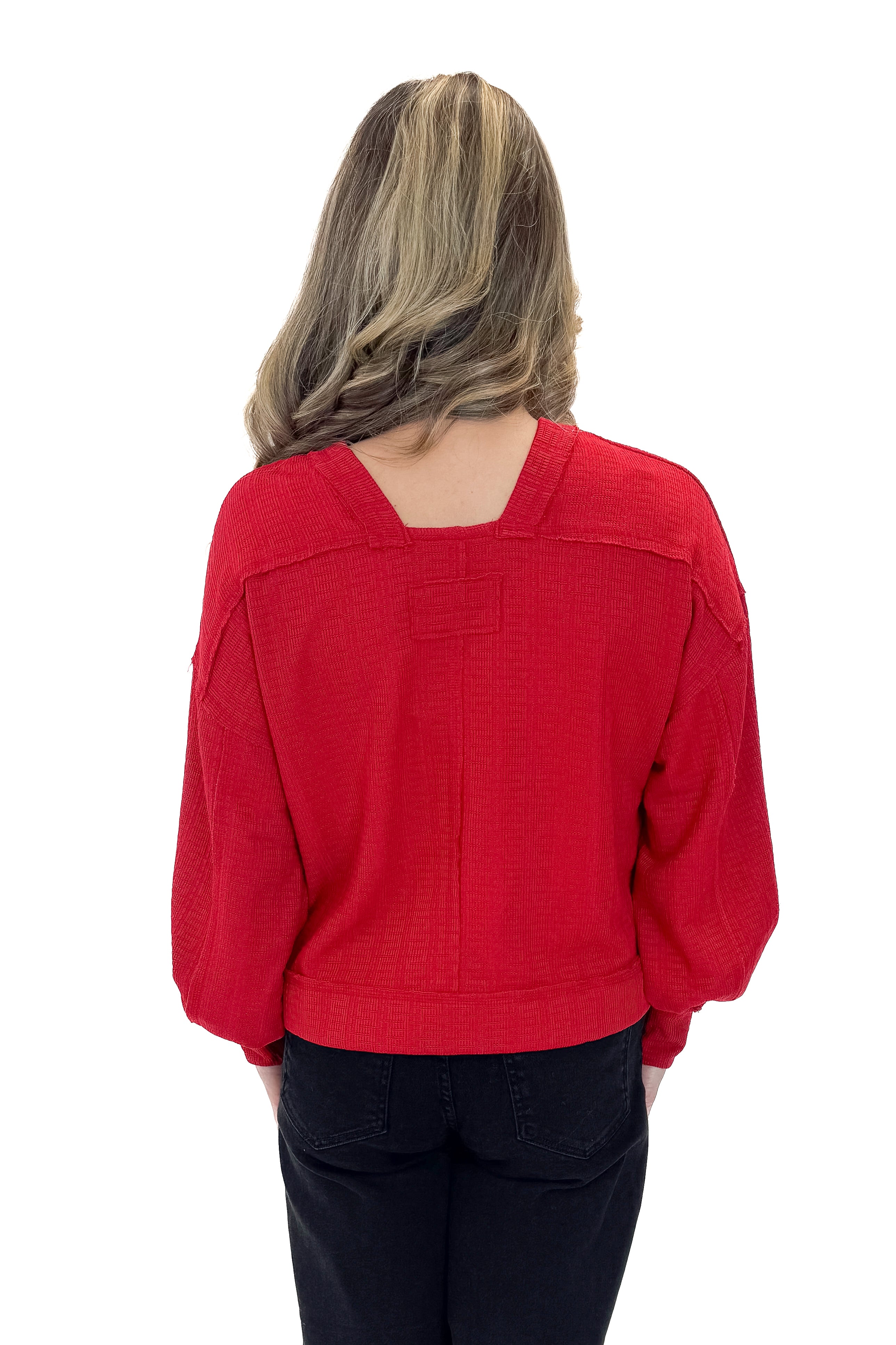 Back view of woman wearing Red Center Seam Textured Top with jeans against white studio background.