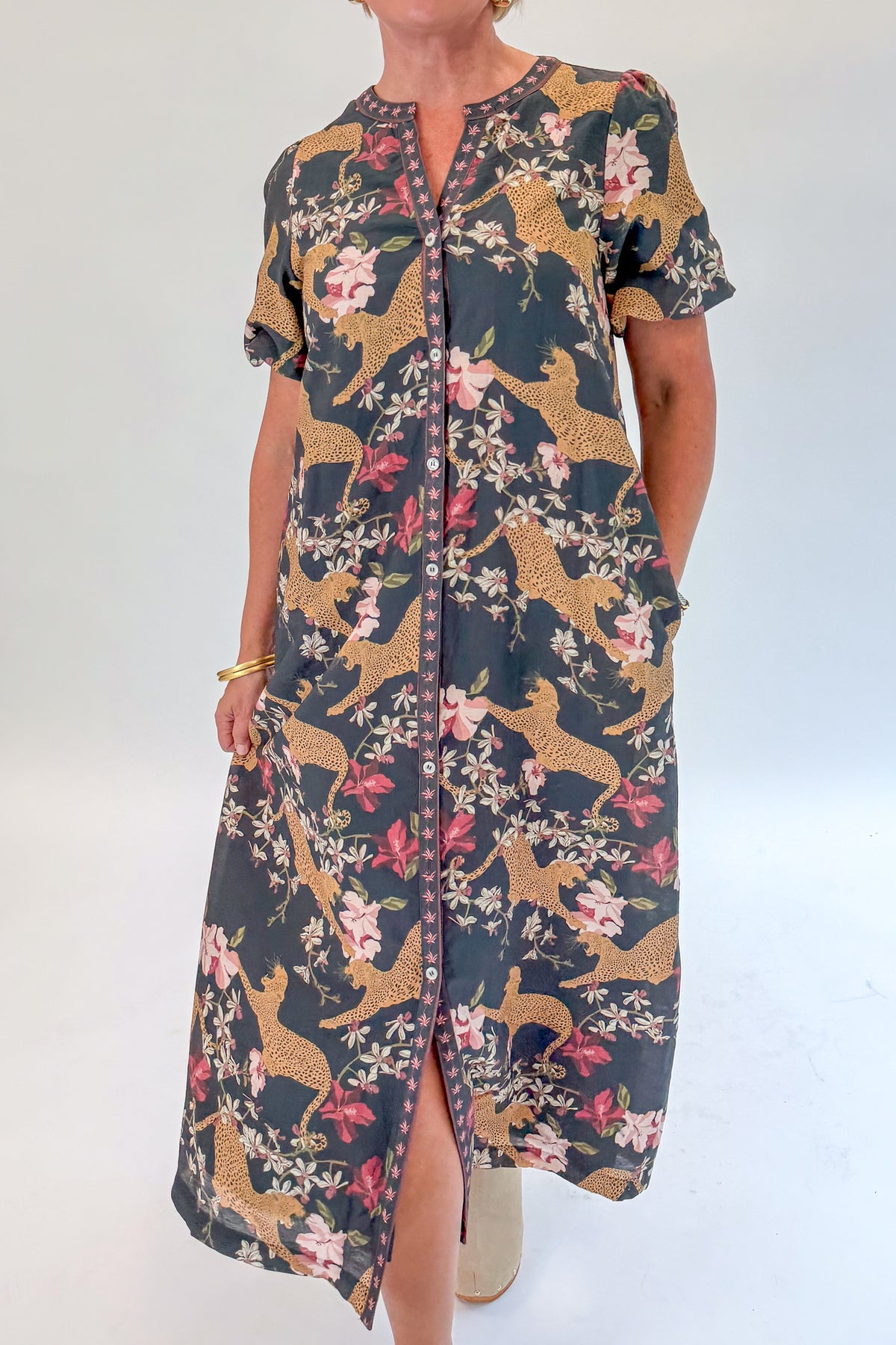 Front detail view of woman wearing Swagger Boutique’s Navy Animal Print Midi Dress with clogs against white studio background.