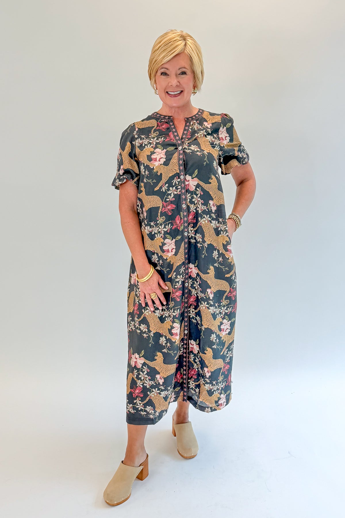 Front view of woman wearing Swagger Boutique’s Navy Animal Print Midi Dress with clogs against white studio background.