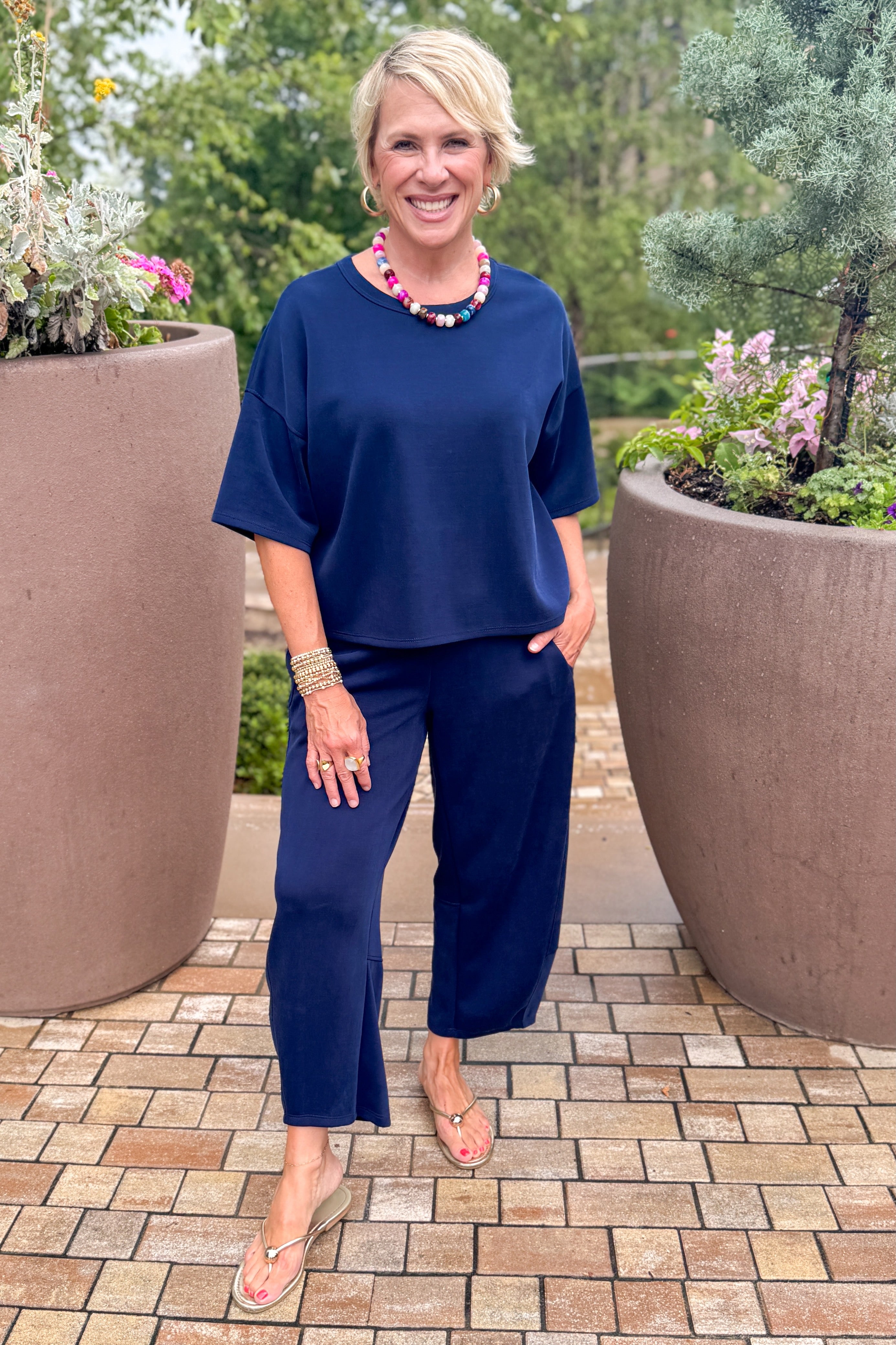 Front view of woman wearing Swagger Boutiqueās Navy Barrel Lounge Pants with Navy Round Neck Short Sleeve Top standing outside at a park.