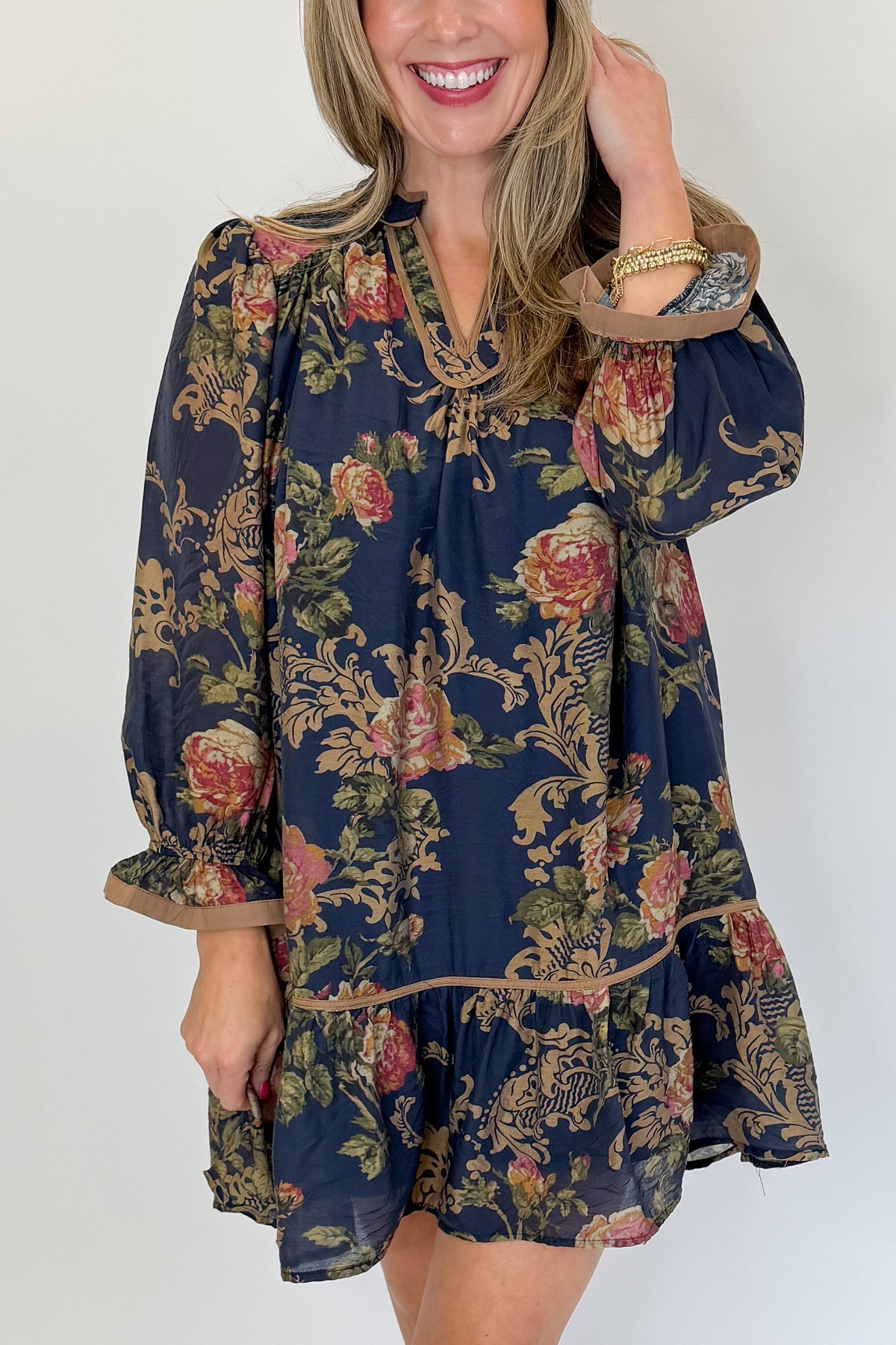 Front detail view of woman wearing Swagger Boutique’s Navy Floral Print Mini Dress with boots against white studio background.