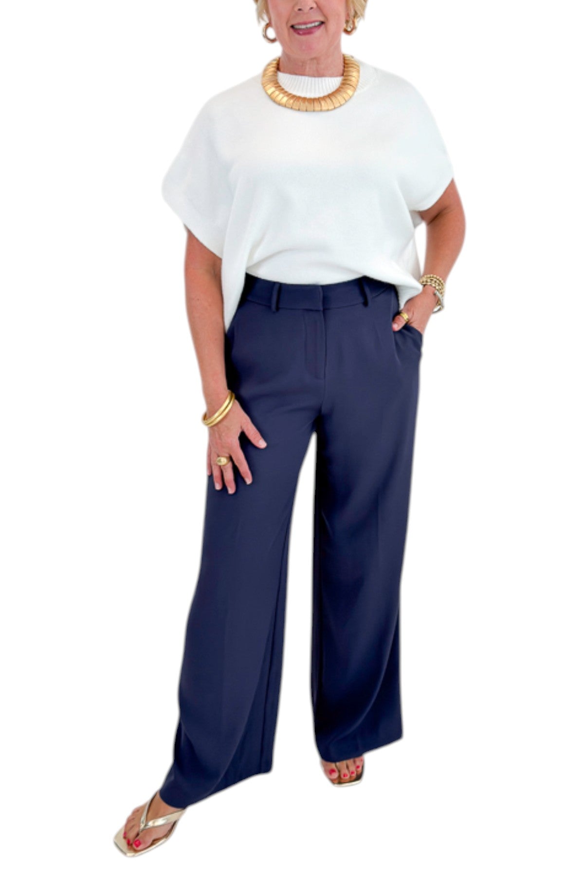 Front view of woman wearing Swagger Boutiqueās Ivory Light Weight Short Sleeve Sweater with Navy High Waisted Trousers by Skies Are Blue against white studio background.