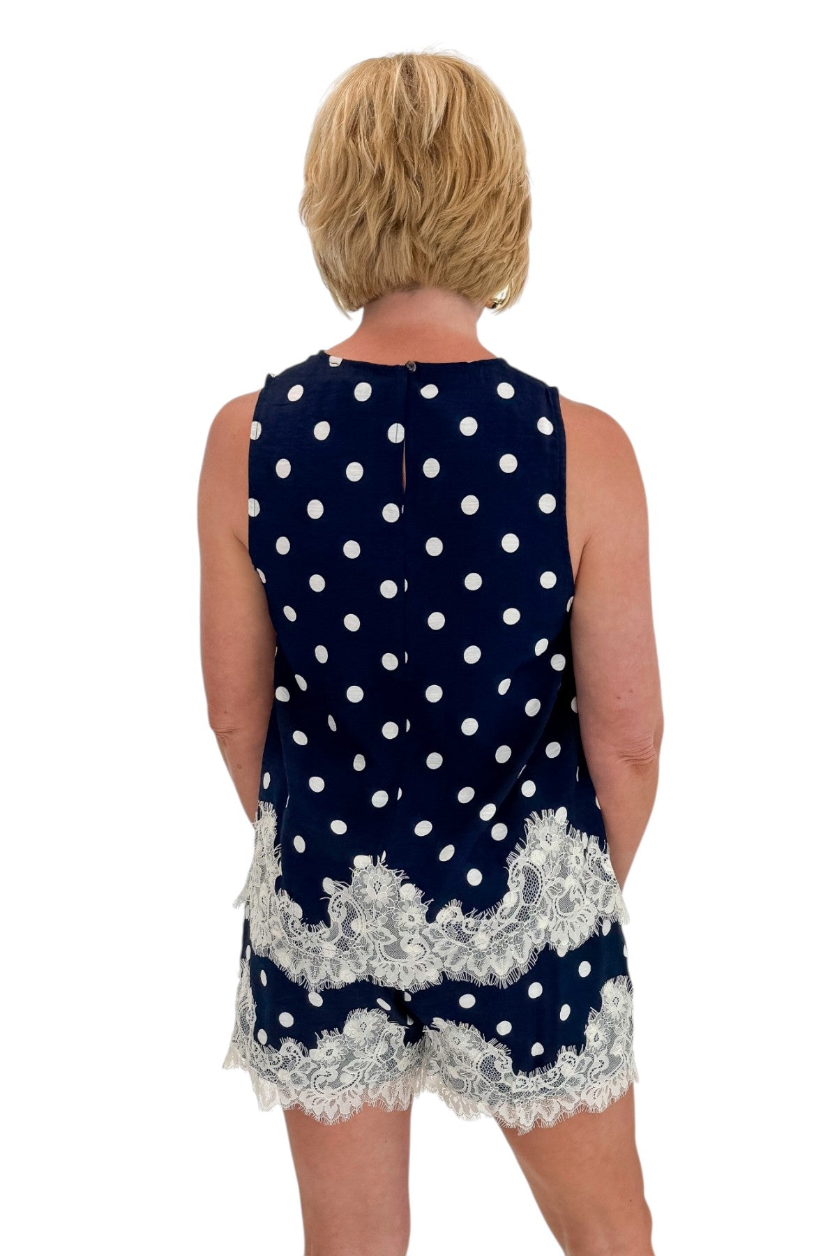 Back view of woman wearing Swagger Boutiqueās Navy Polka Dot Lace Trim Shorts by Entro with matching tank against white studio background.
