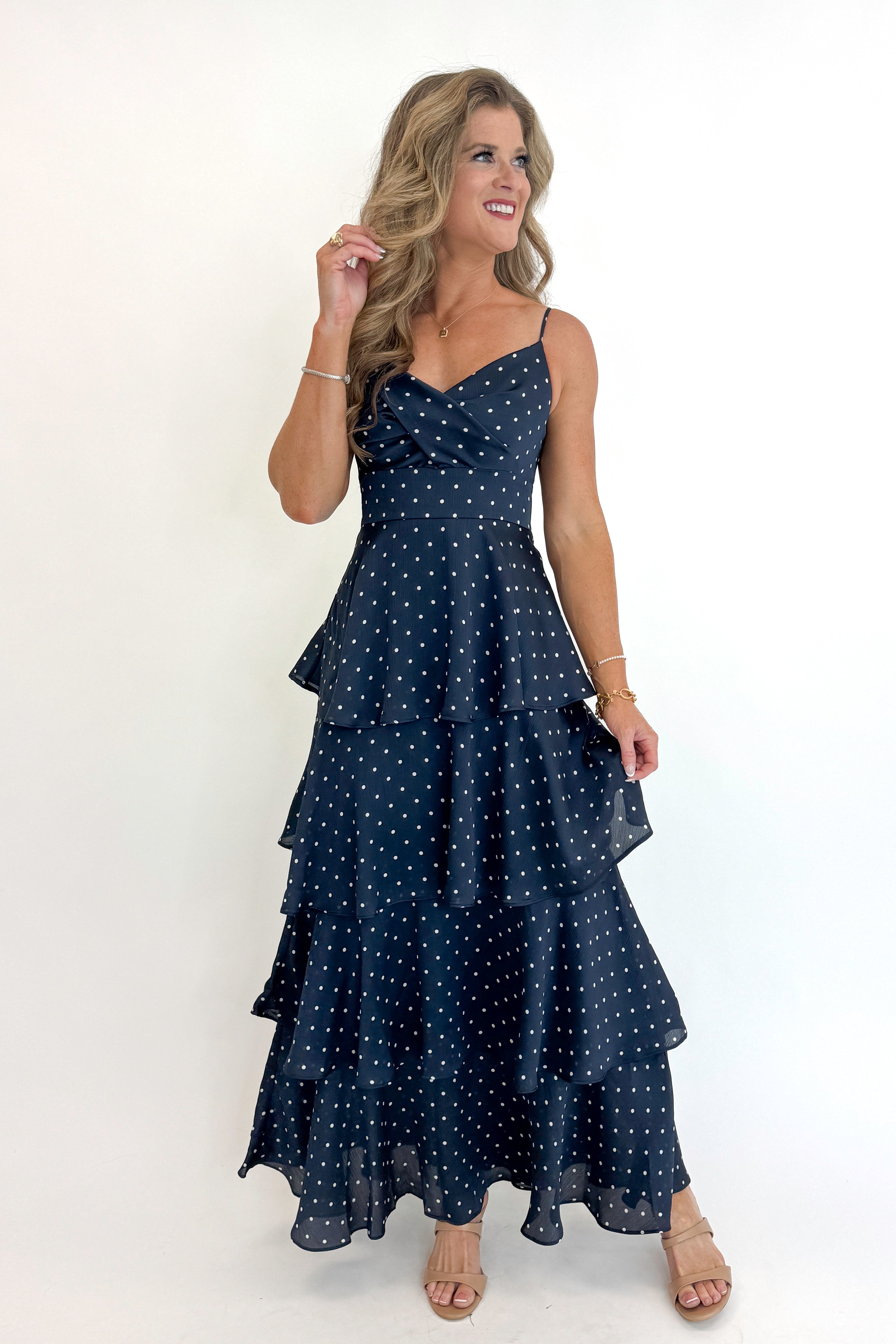 Front view of woman wearing Swagger Boutiqueās Navy Polka Dot Tiered Maxi Dress against white studio background.