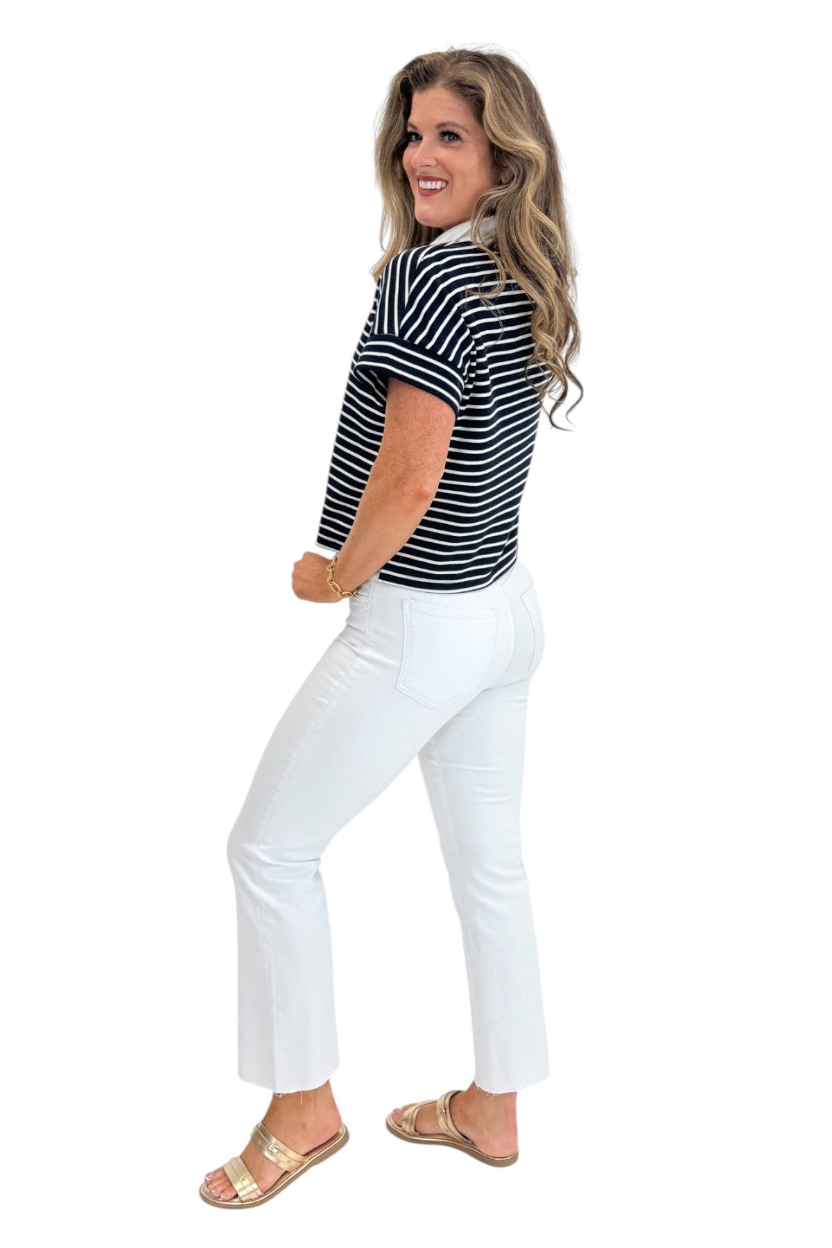 Side view of woman wearing Swagger Boutiqueβs Navy Striped Collared Top by Entro with jeans against white studio background.