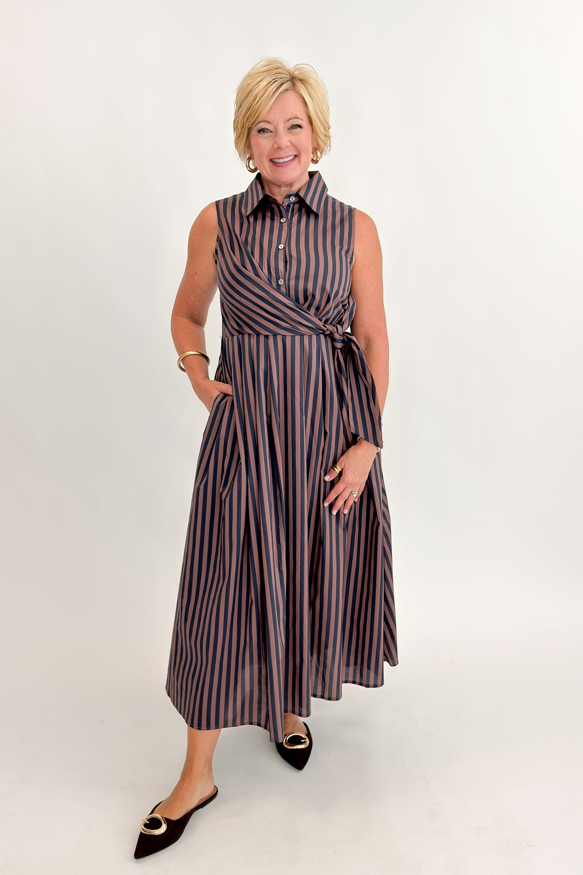 Front view of woman wearing Swagger Boutique’s Navy & Brown Striped Midi Dress With Tie by Entro against white studio background.