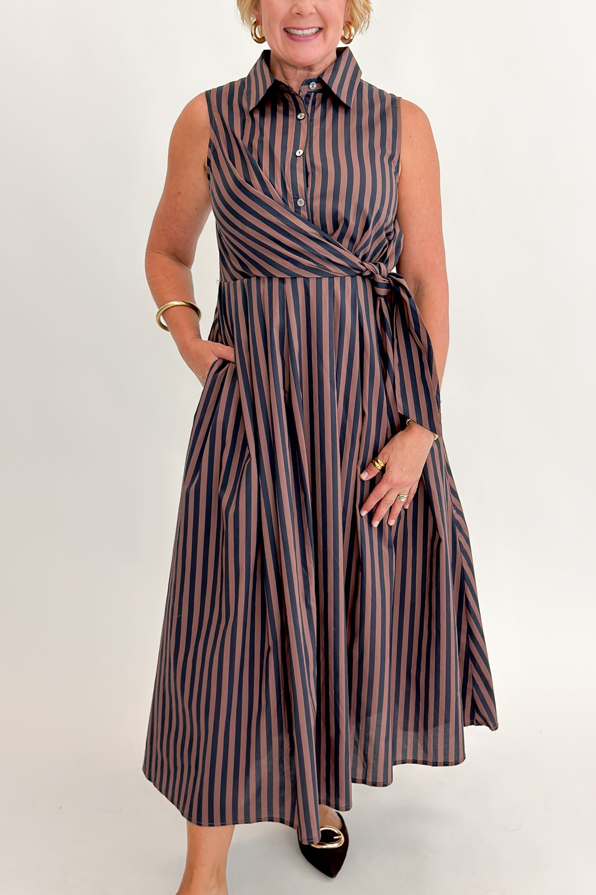 Front detail view of woman wearing Swagger Boutique’s Navy & Brown Striped Midi Dress With Tie by Entro against white studio background.