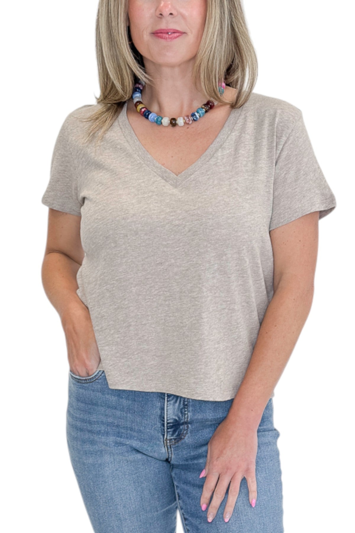 Front detail view of woman wearing Swagger Boutique’s Heather Ash Nomad V-Neck Tee by Z Supply with jeans against white studio background.