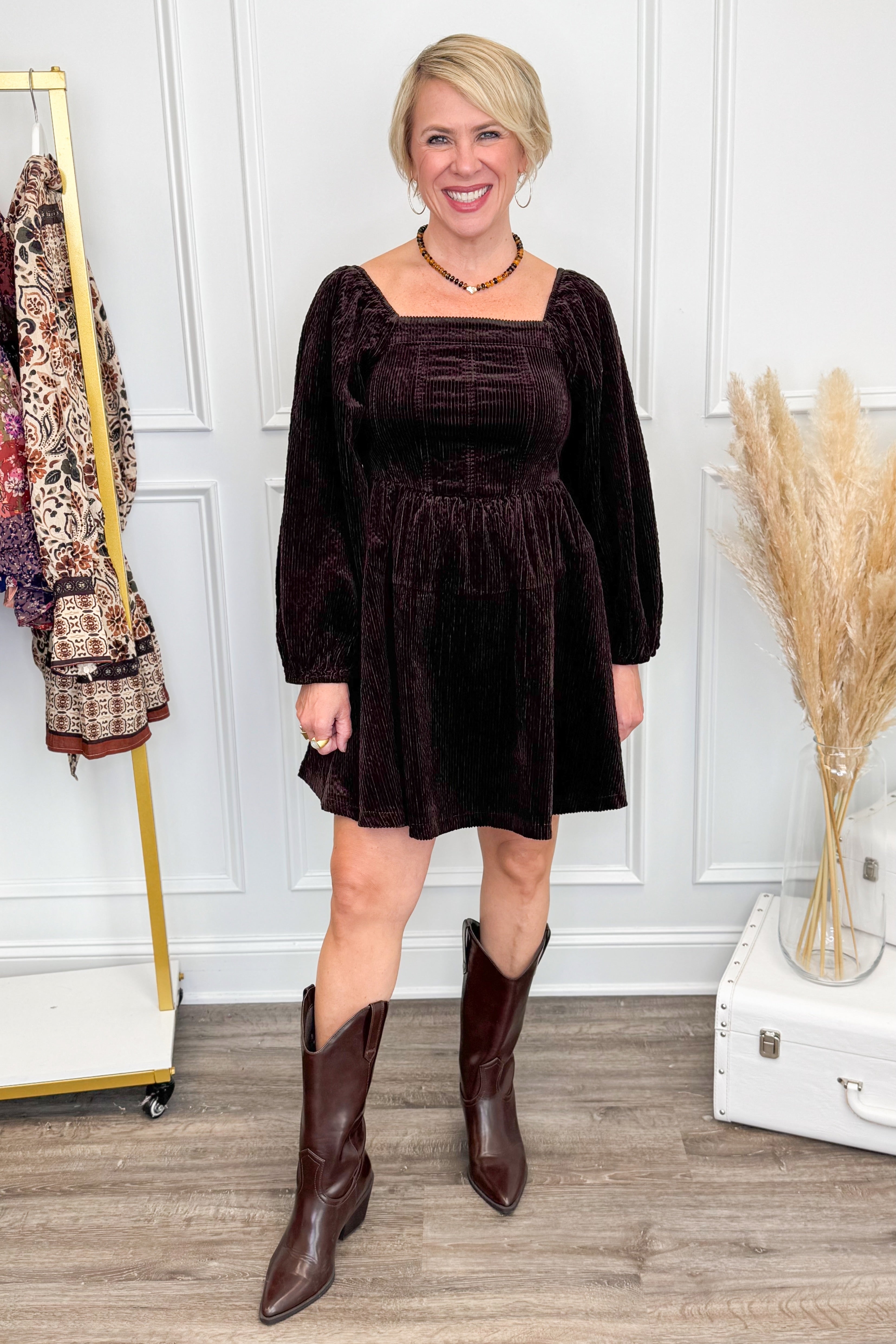Woman wearing Brown Corduroy Puff Sleeve Dress and boots with decor in background.