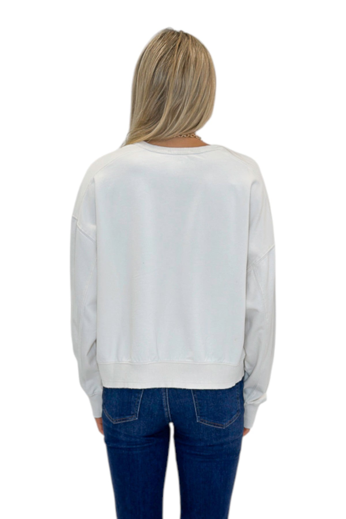 Back view of woman wearing Swagger Boutiqueās Off White Ribbed Detail Sweatshirt with jeans against white studio background.