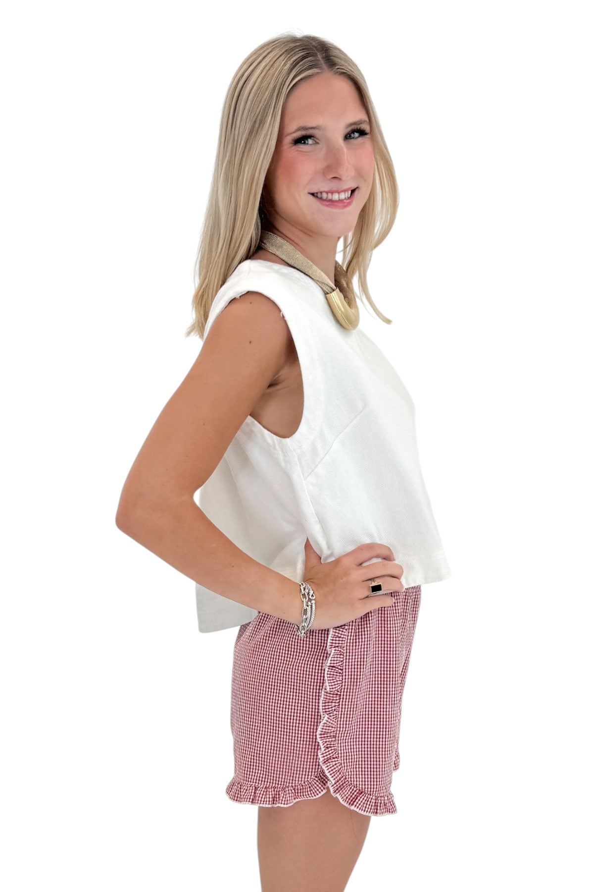 Side view of woman wearing Swagger Boutiqueās Red & White Gingham Ruffle Shorts with Off White Cap Sleeve Top by entro against white studio background.