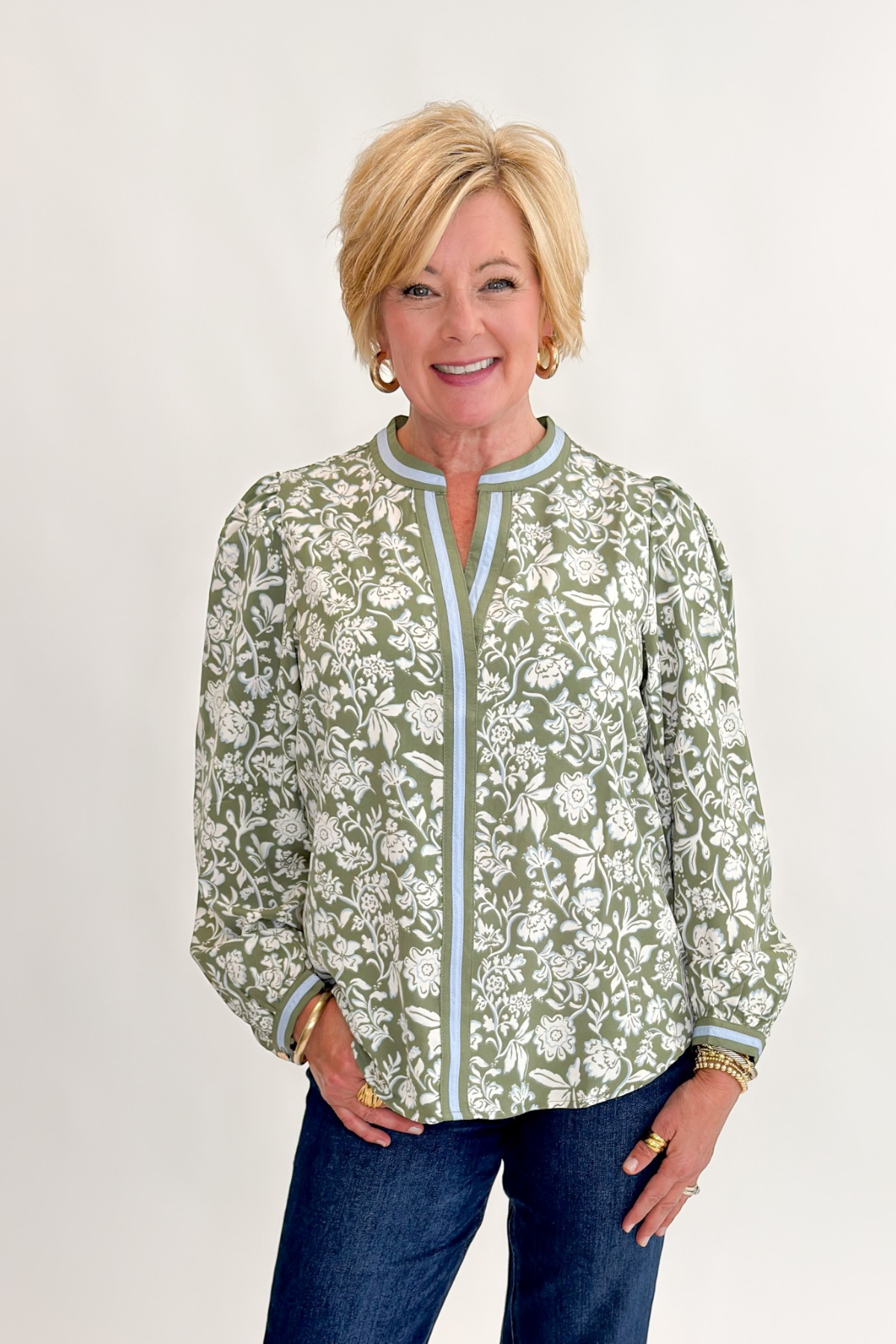 Front view of woman wearing Swagger Boutique’s Olive Floral V-Neck Top with jeans against white studio background.