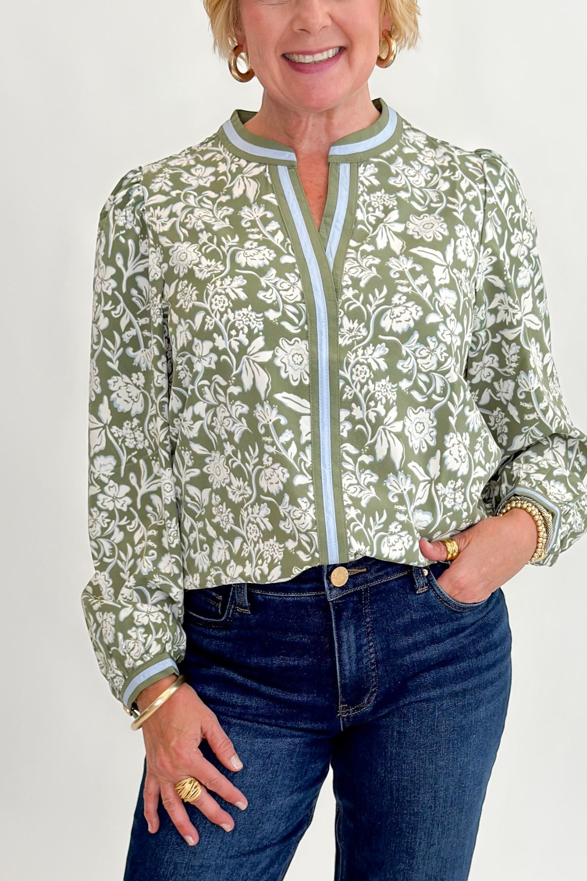 Front detail view of woman wearing Swagger Boutique’s Olive Floral V-Neck Top with jeans against white studio background.