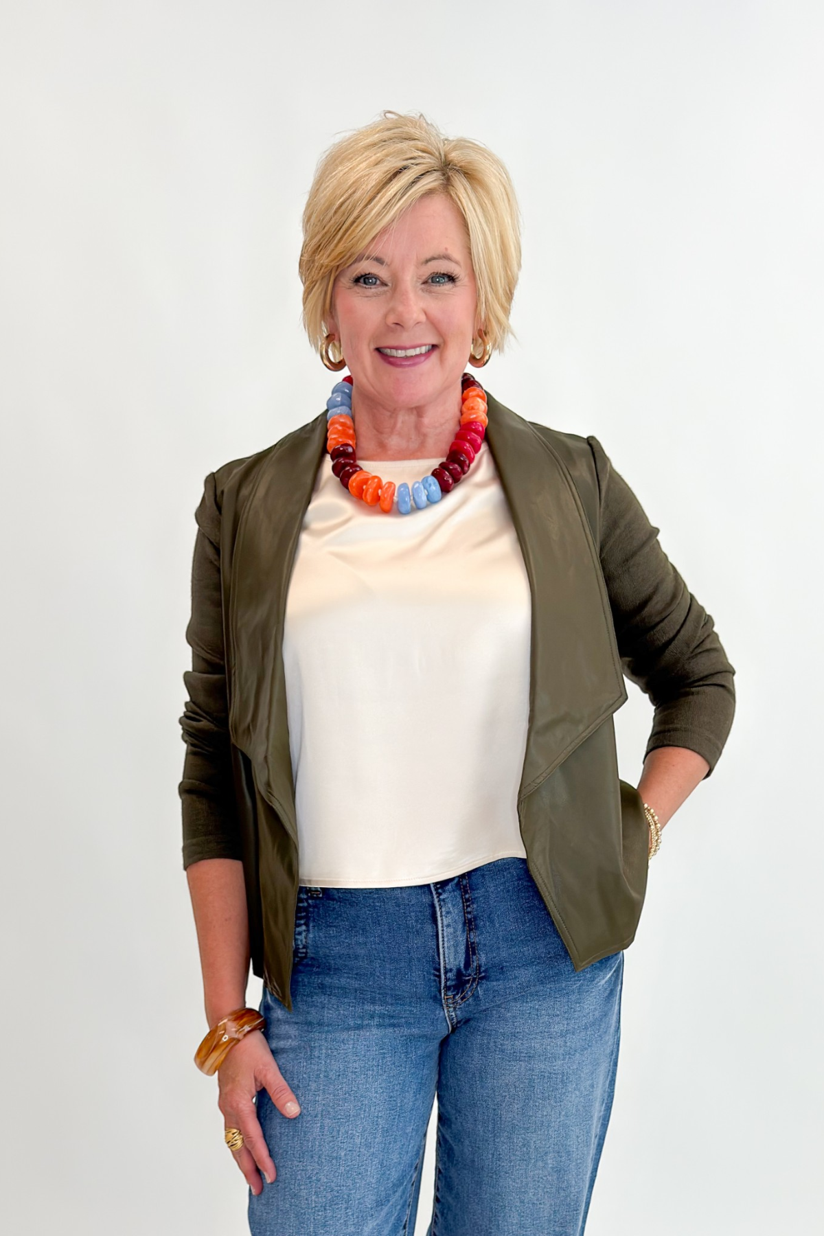 Front view of woman wearing Swagger Boutique’s Olive Knit & Faux Leather Draped Jacket with Maya Wide Leg Jeans In Medium Wash- Journey by Kut from the Kloth against white studio background.