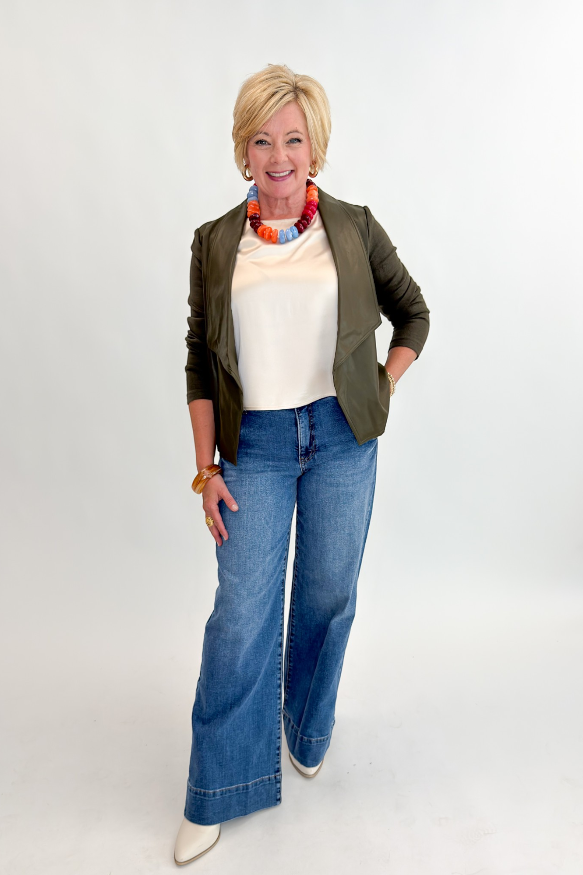 Front view of woman wearing Swagger Boutique’s Olive Knit & Faux Leather Draped Jacket with Maya Wide Leg Jeans In Medium Wash- Journey by Kut from the Kloth against white studio background.
