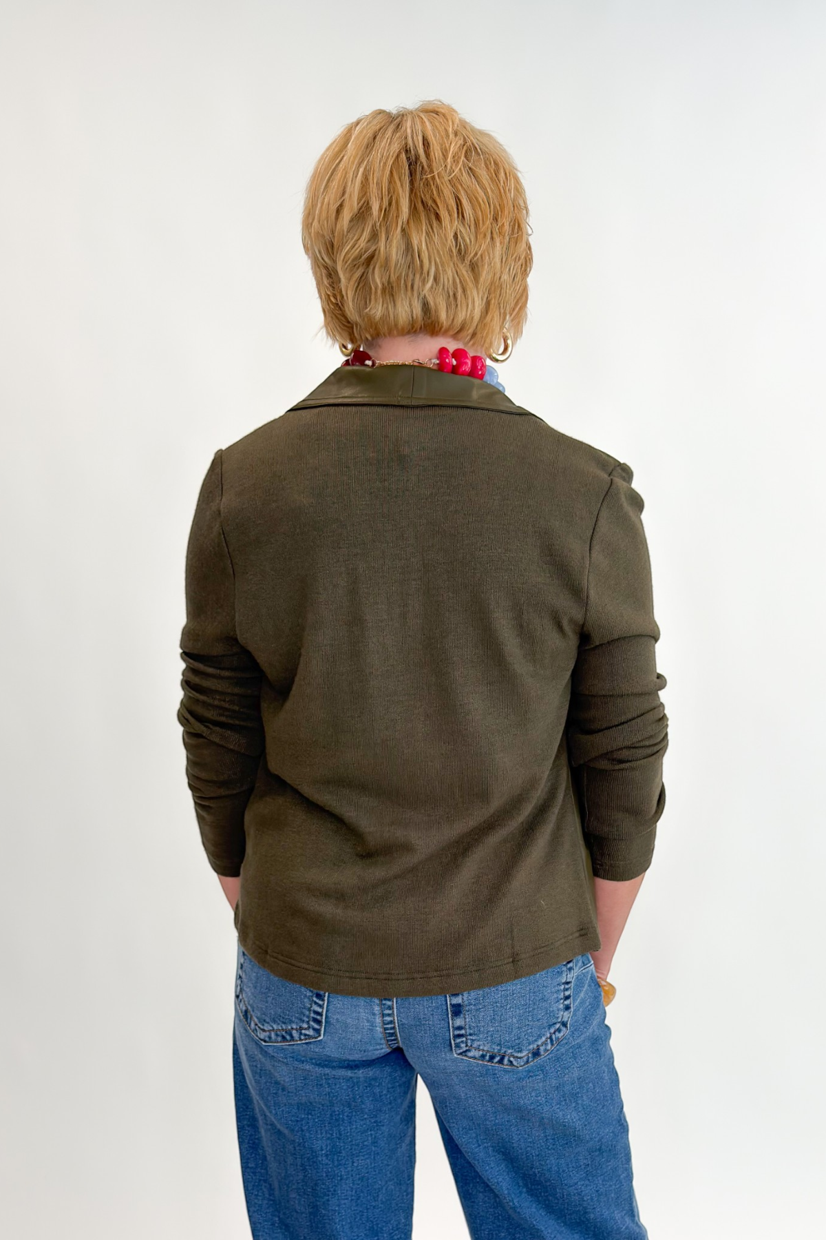 Back view of woman wearing Swagger Boutique’s Olive Knit & Faux Leather Draped Jacket with Maya Wide Leg Jeans In Medium Wash- Journey by Kut from the Kloth against white studio background.