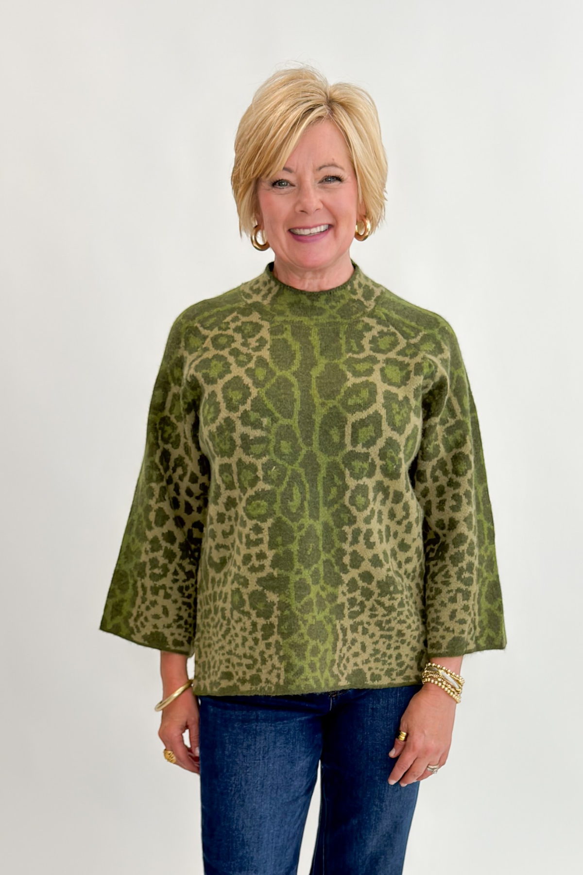Front view of woman wearing Swagger Boutique’s Olive Leopard Print Mock Neck Sweater by Entro with jeans against white studio background.
