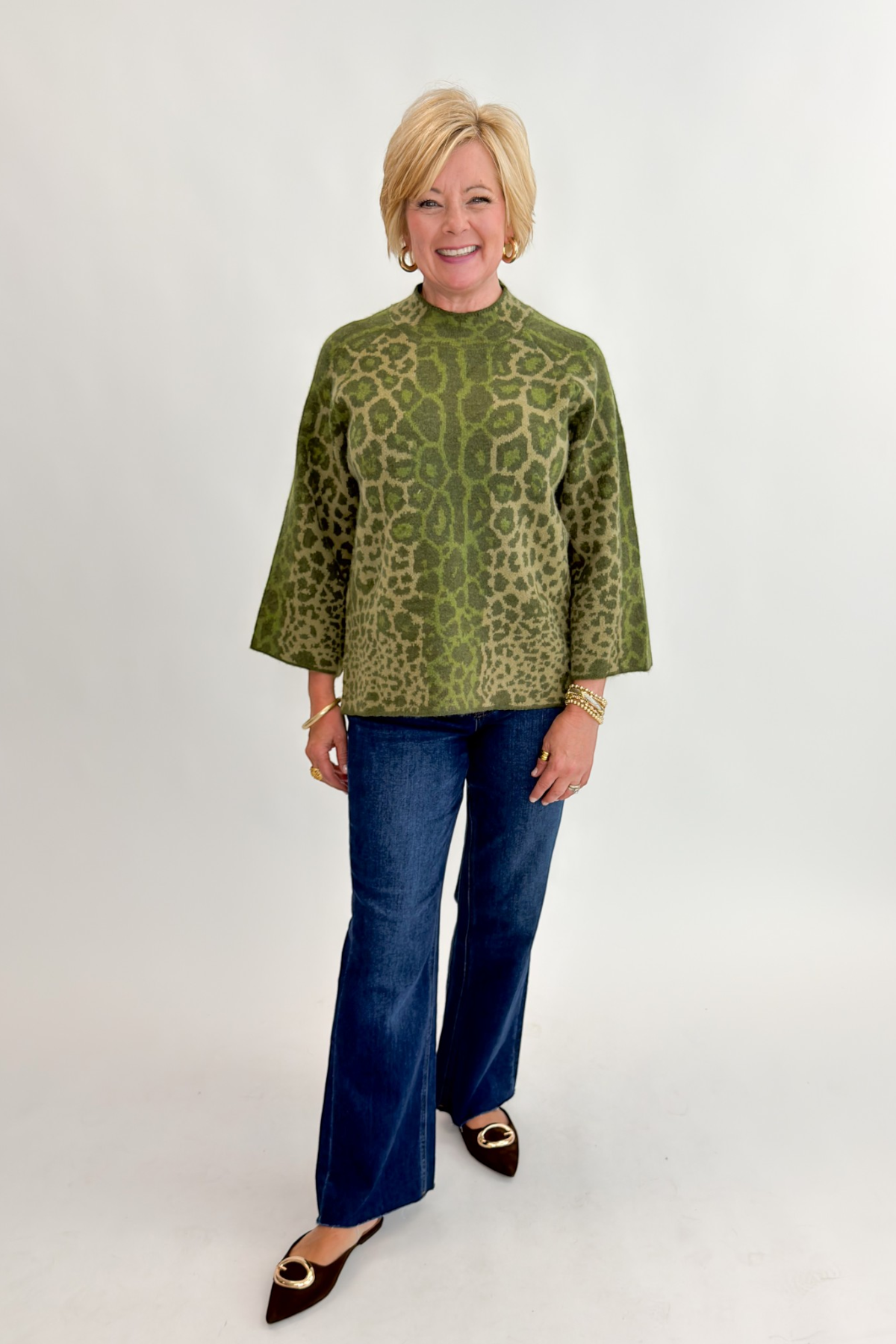 Front view of woman wearing Swagger Boutique’s Olive Leopard Print Mock Neck Sweater by Entro with jeans against white studio background.