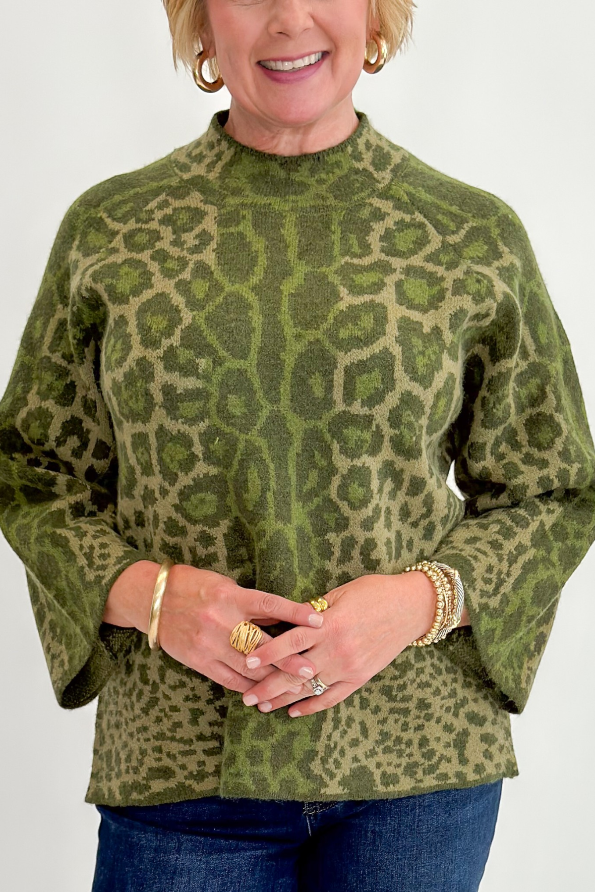 Front detail view of woman wearing Swagger Boutique’s Olive Leopard Print Mock Neck Sweater by Entro with jeans against white studio background.