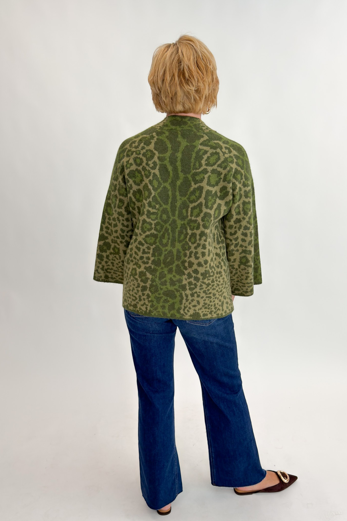 Back view of woman wearing Swagger Boutique’s Olive Leopard Print Mock Neck Sweater by Entro with jeans against white studio background.