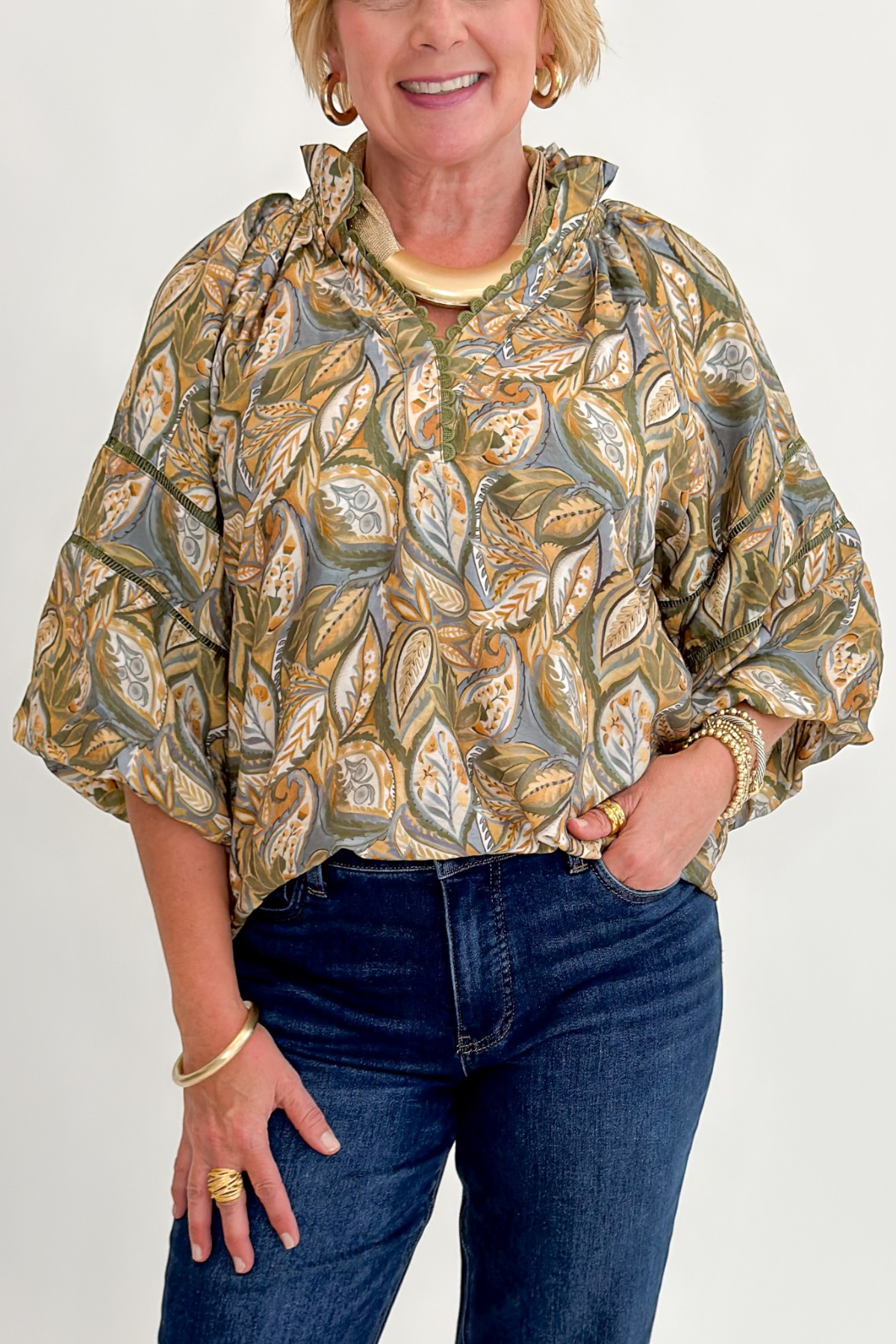 Front detail view of woman wearing Swagger Boutique’s Olive Printed 3/4 Sleeve Top with jeans against white studio background.