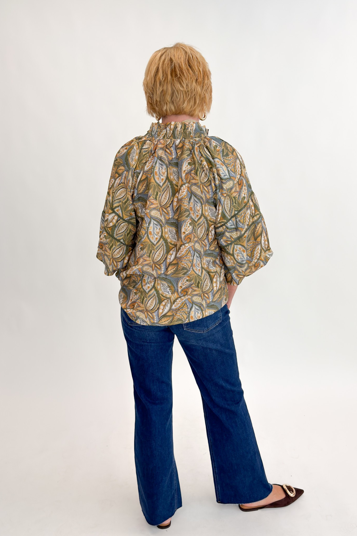 Back view of woman wearing Swagger Boutique’s Olive Printed 3/4 Sleeve Top with jeans against white studio background.