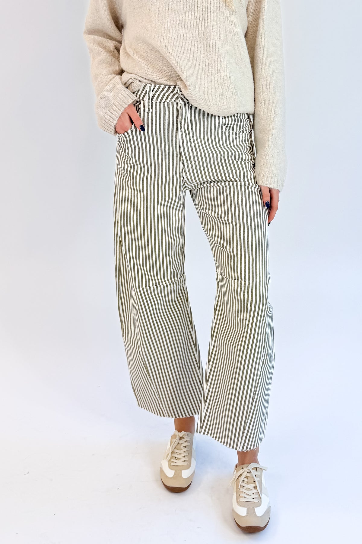Front detail view of woman wearing Swagger Boutique’s top with Olive Striped Barrel Jeans by Just Black Denim against white studio background.