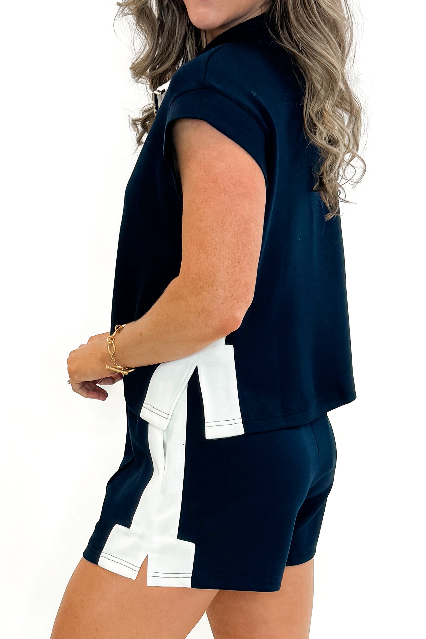 Side view of woman wearing Navy With White Color Block 1/4 Zip Sweatshirt by Entro with matching Navy With White Color Block Stripe Shorts by Entro against white studio background.