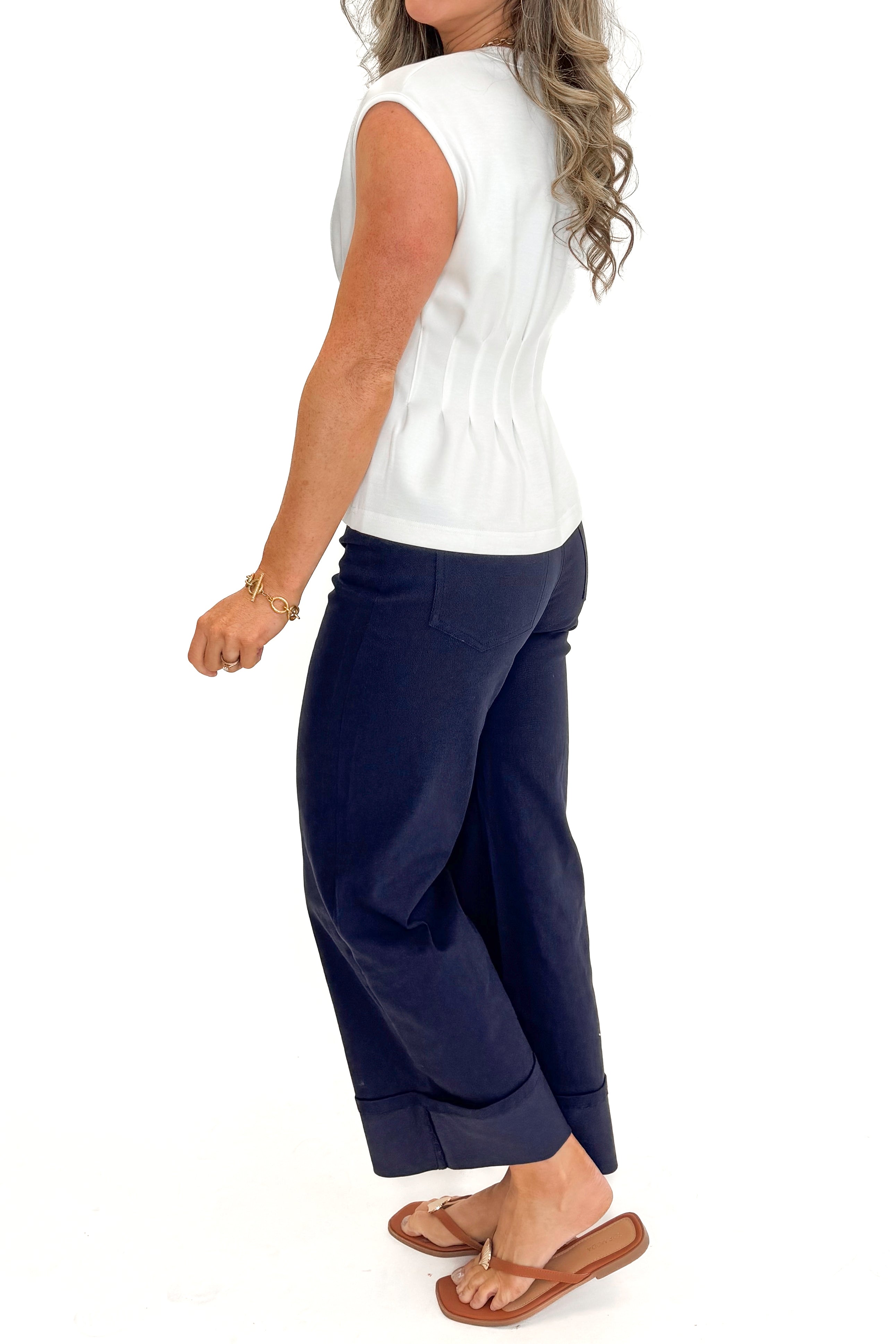 Side view of woman wearing Navy Cuffed Jeans by Entro with white top against white studio background.