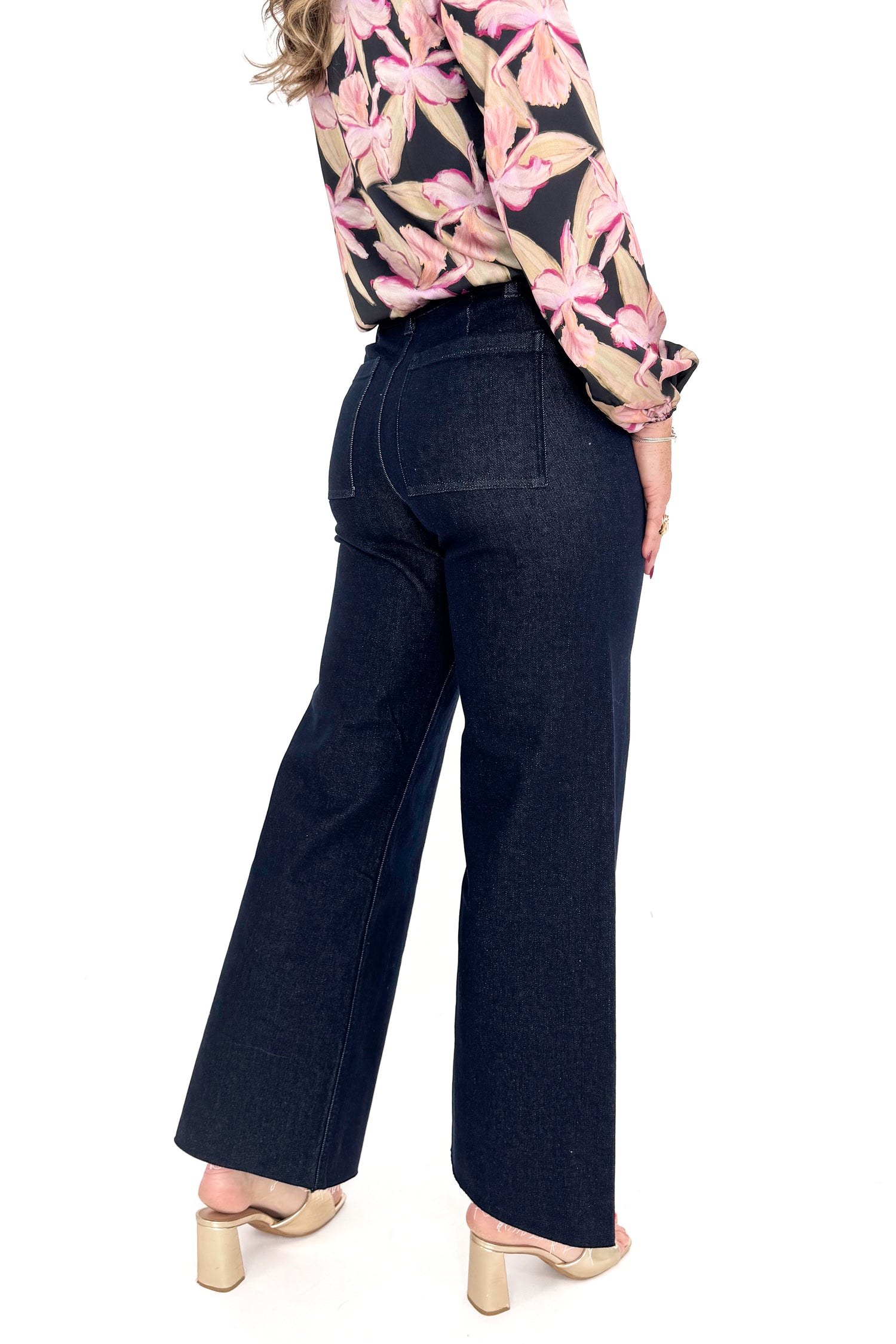 Close up view of woman in a studio wearing Dark Indigo Wide Leg Jeans and print top with a white background.