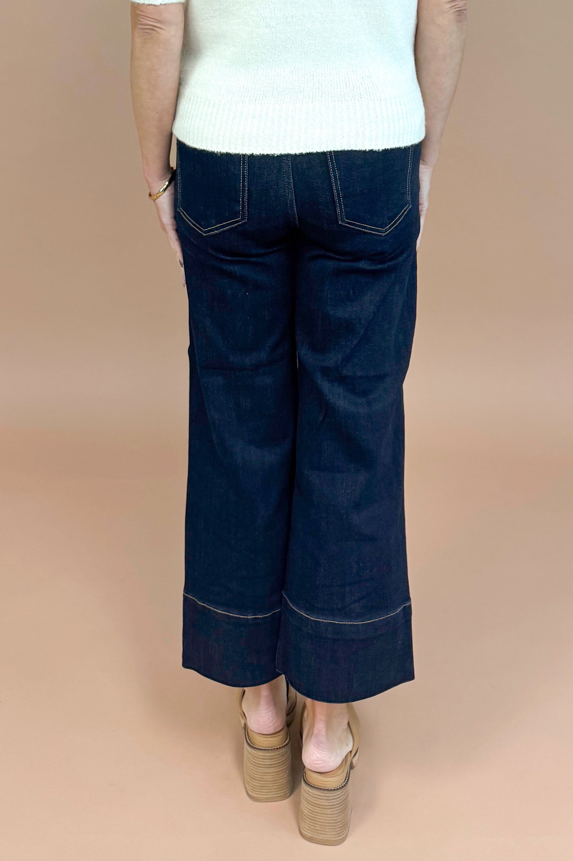 Navy blue wide-leg jeans worn by a person on a beige background