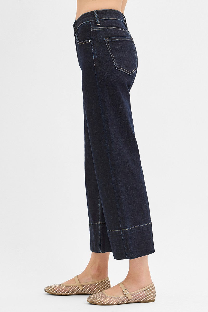Dark blue jeans worn by a person on a white background