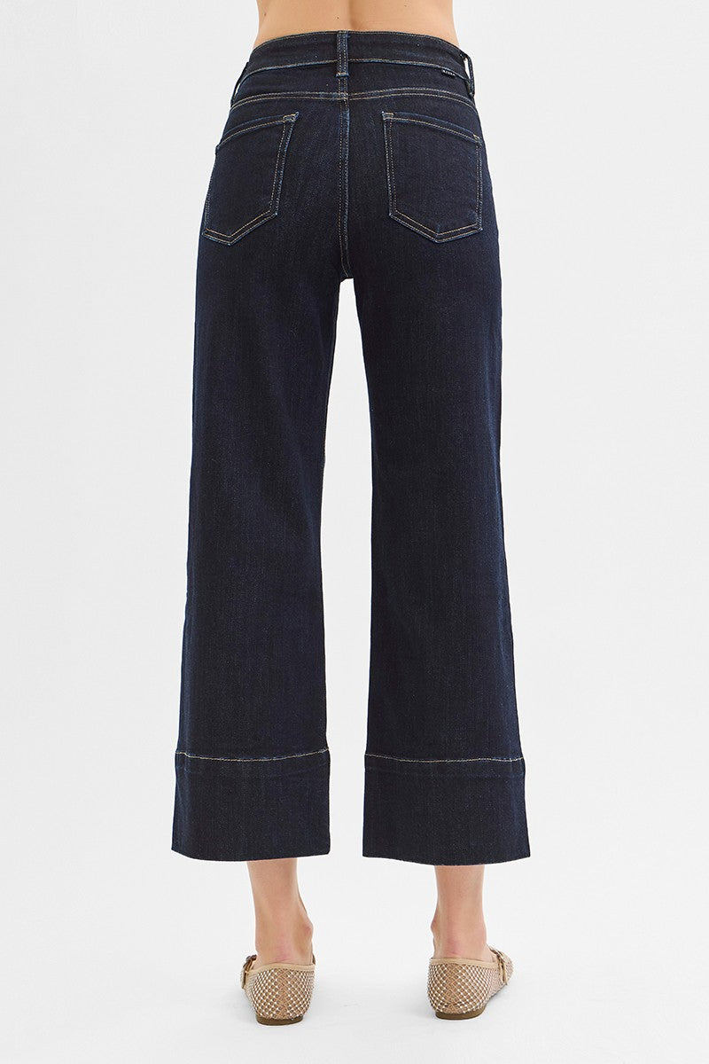 Dark blue jeans worn by a person on a white background